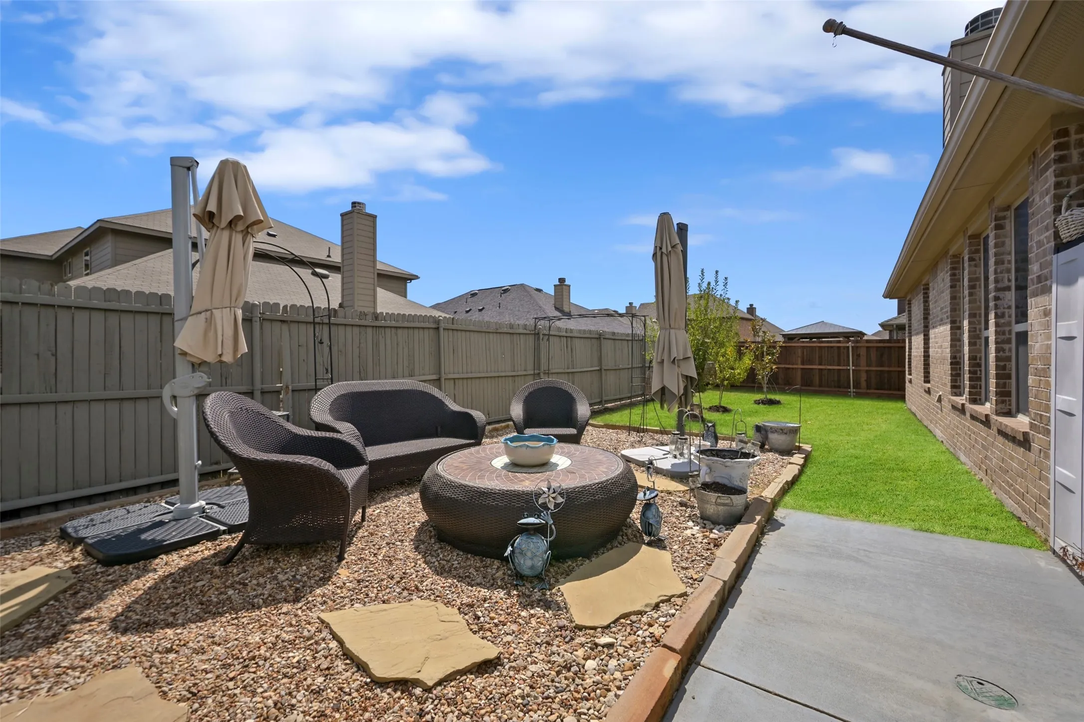 Expansive backyard featuring a manicured lawn, gravel patio, and concrete walkway