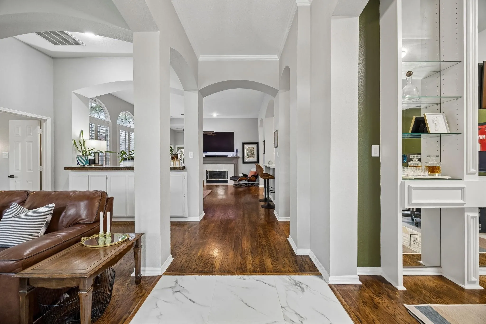 Open-concept living space featuring soaring ceilings with architectural arches, white structural columns, and rich wood-finish flooring throughout