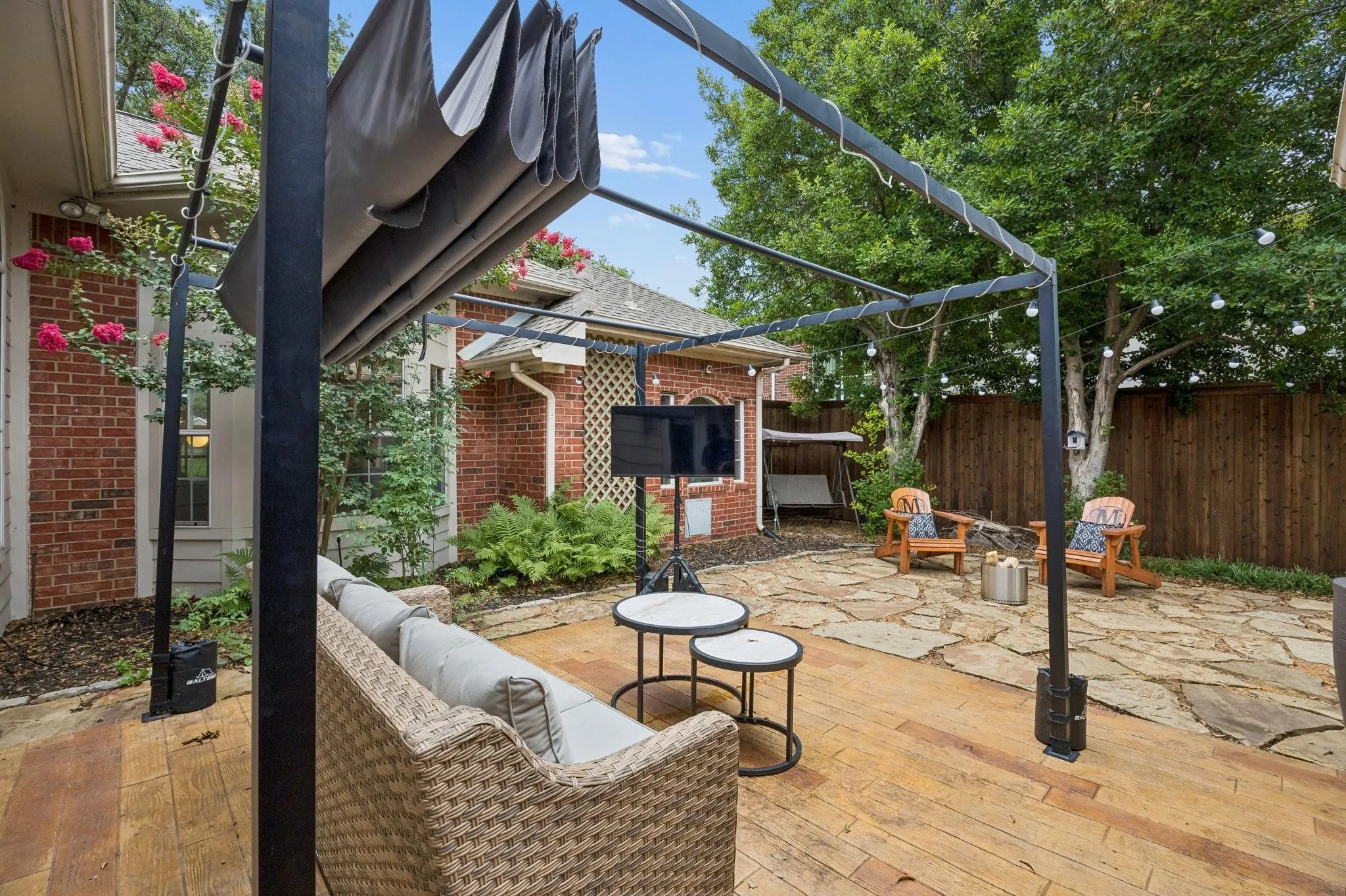 Outdoor living space featuring a retractable shade canopy, wood-finish decking, and flagstone patio