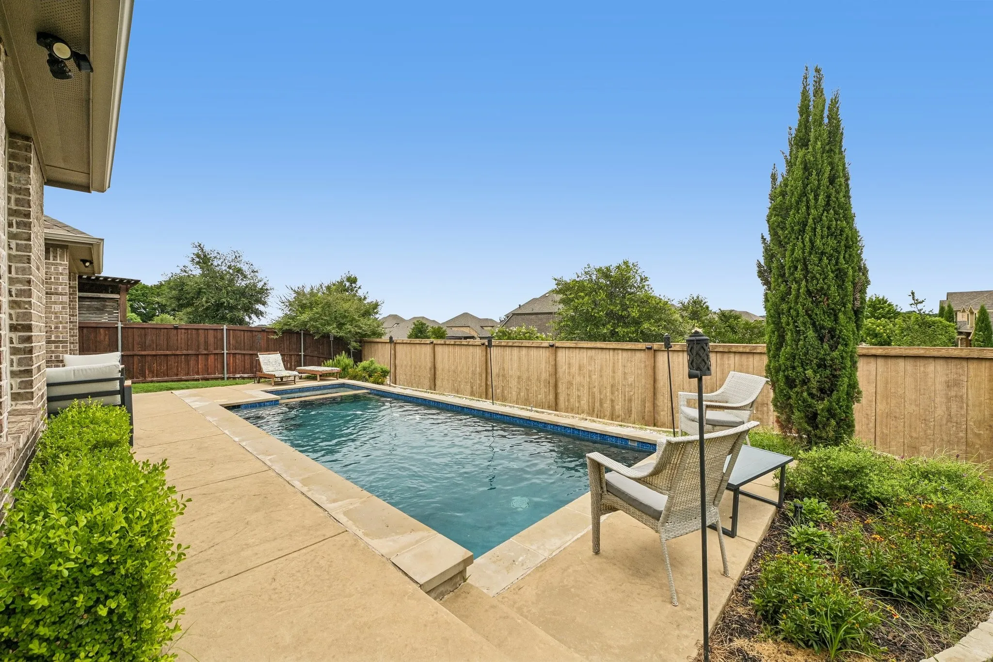 Rectangular swimming pool with integrated spa, concrete decking, and established perimeter landscaping