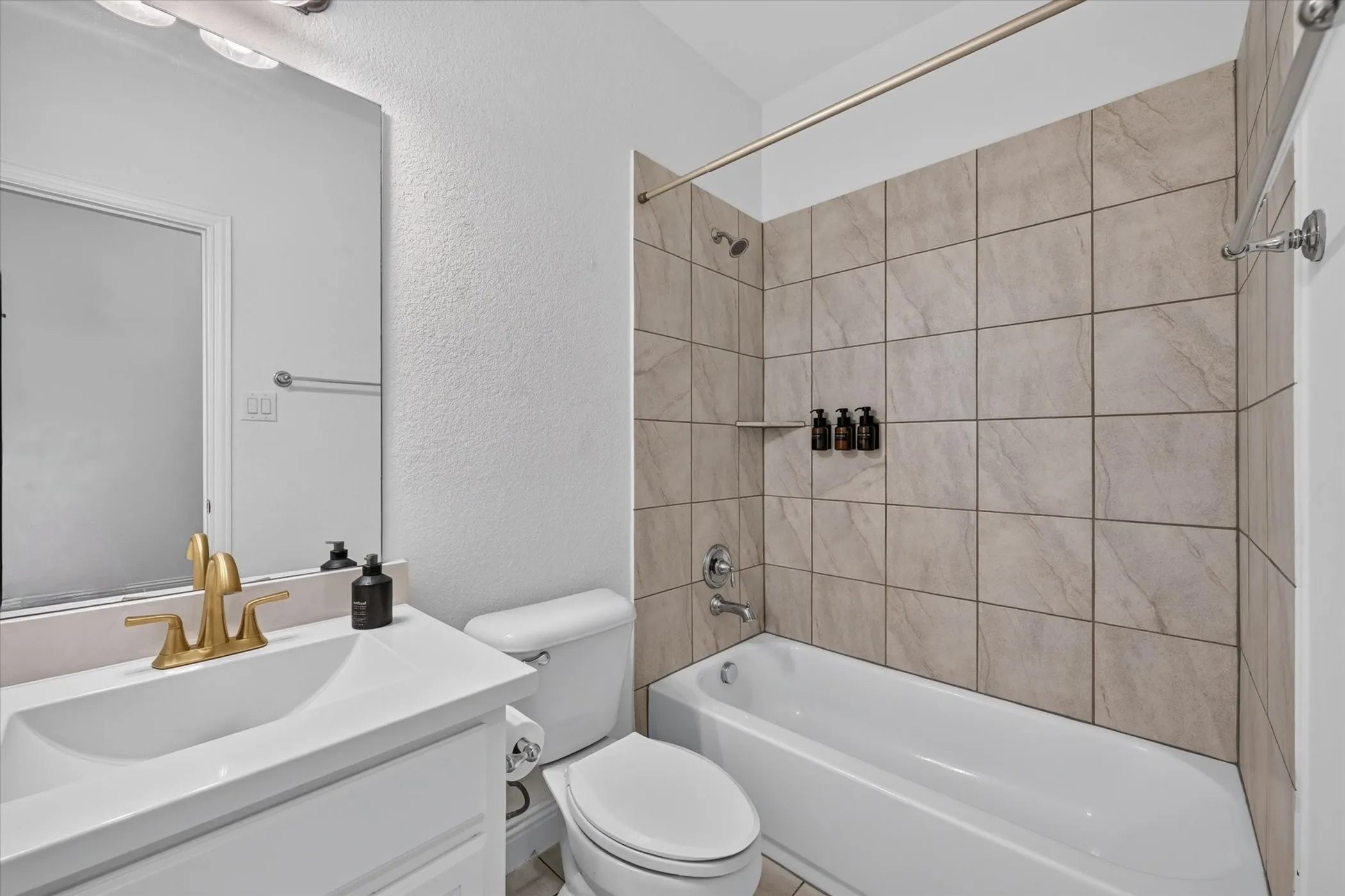 White vanity with integrated sink, brass-finish faucet, and coordinating mirror