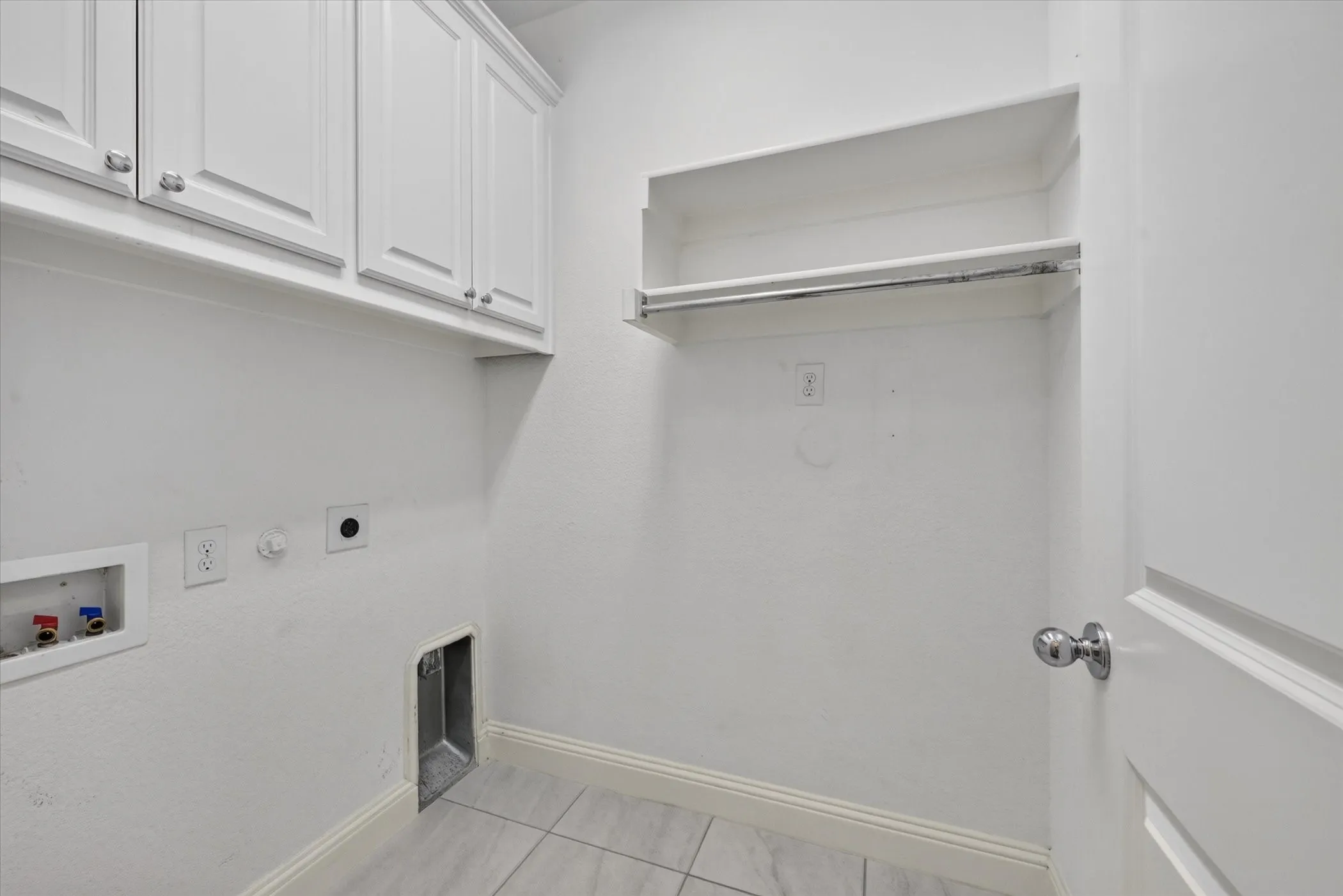 Dedicated laundry room featuring white cabinetry with chrome hardware, tile flooring, built-in shelving, and a pet door for convenient access