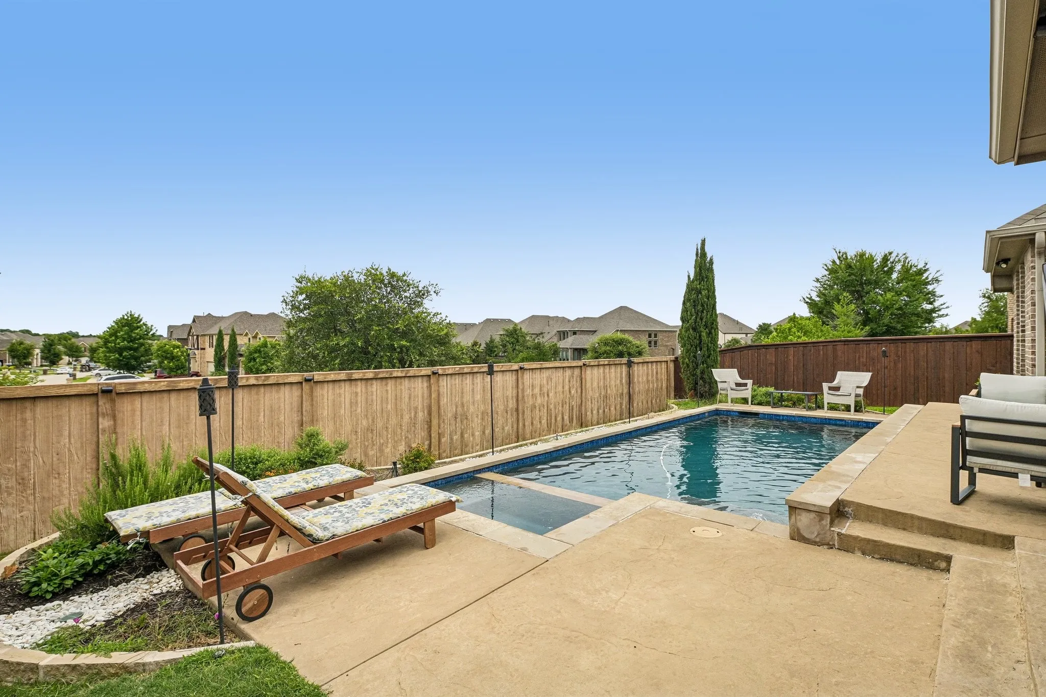 Rectangular in-ground swimming pool with concrete surround and a stone-clad raised edge