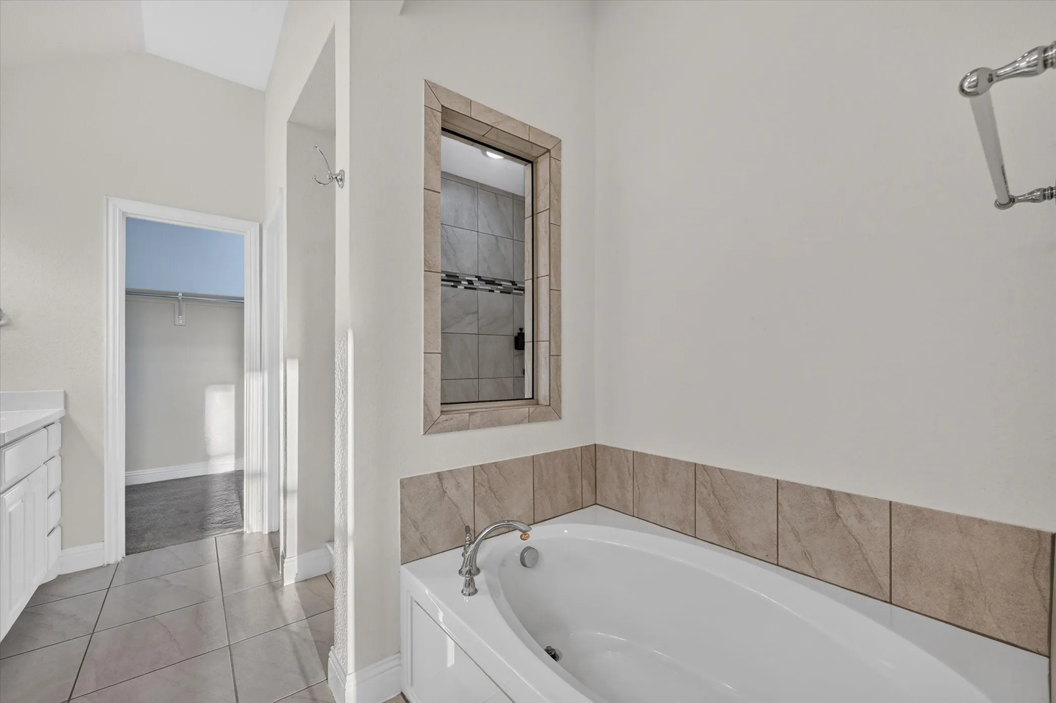 Soaking tub with tiled surround, tile flooring, and vaulted ceiling