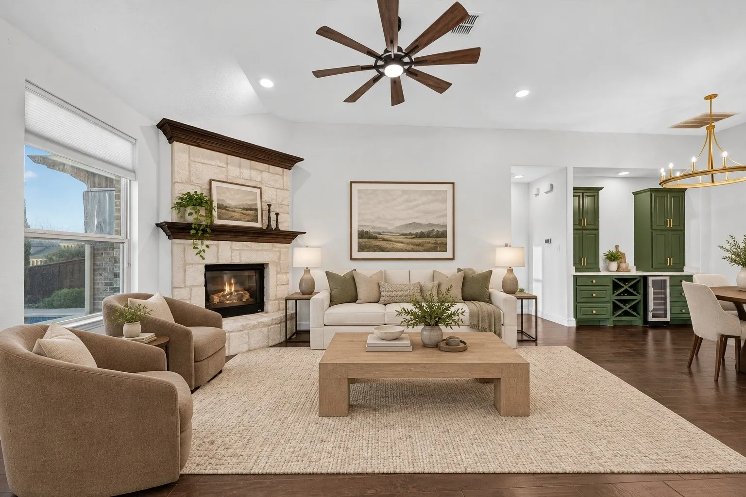 Expansive living area with wood-finish flooring, a stone-clad fireplace, and a contemporary ceiling fan