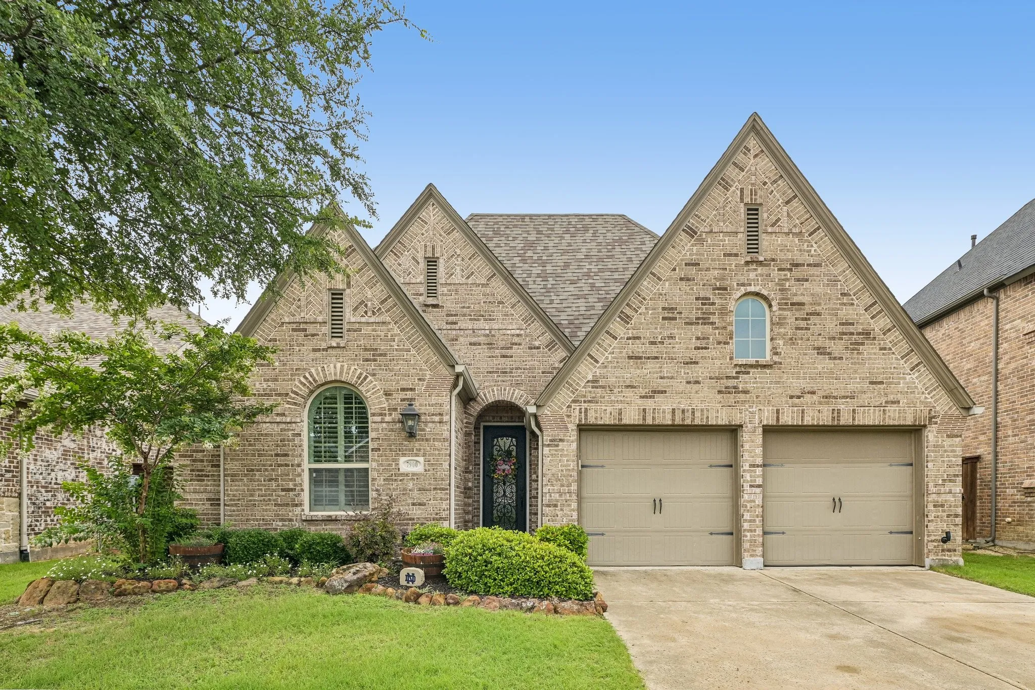 Brick exterior with arched window details, a two-car garage, and a gabled roofline