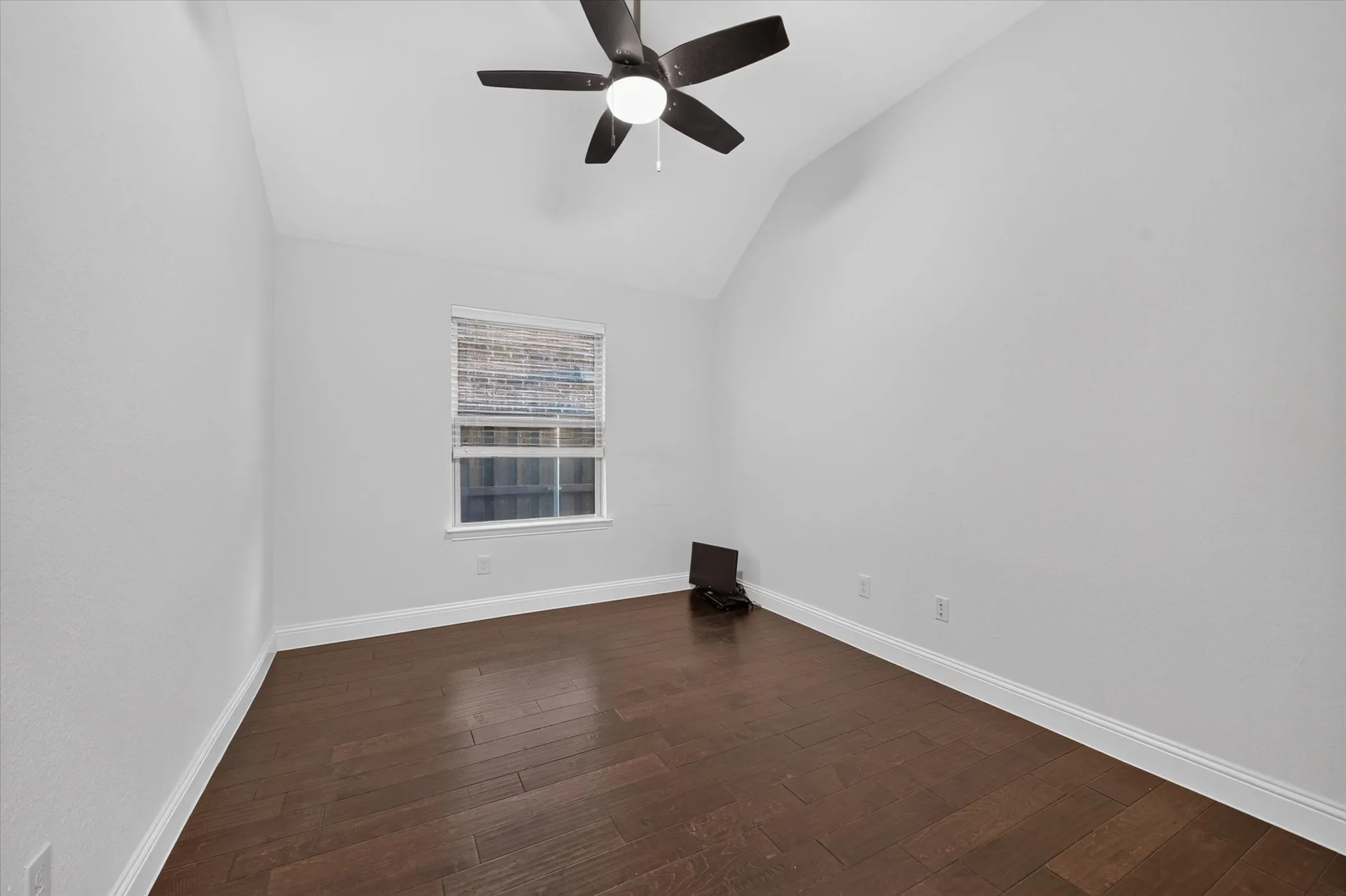 Vaulted ceiling, ceiling fan, wood-finish flooring, white trim, and a window with blinds