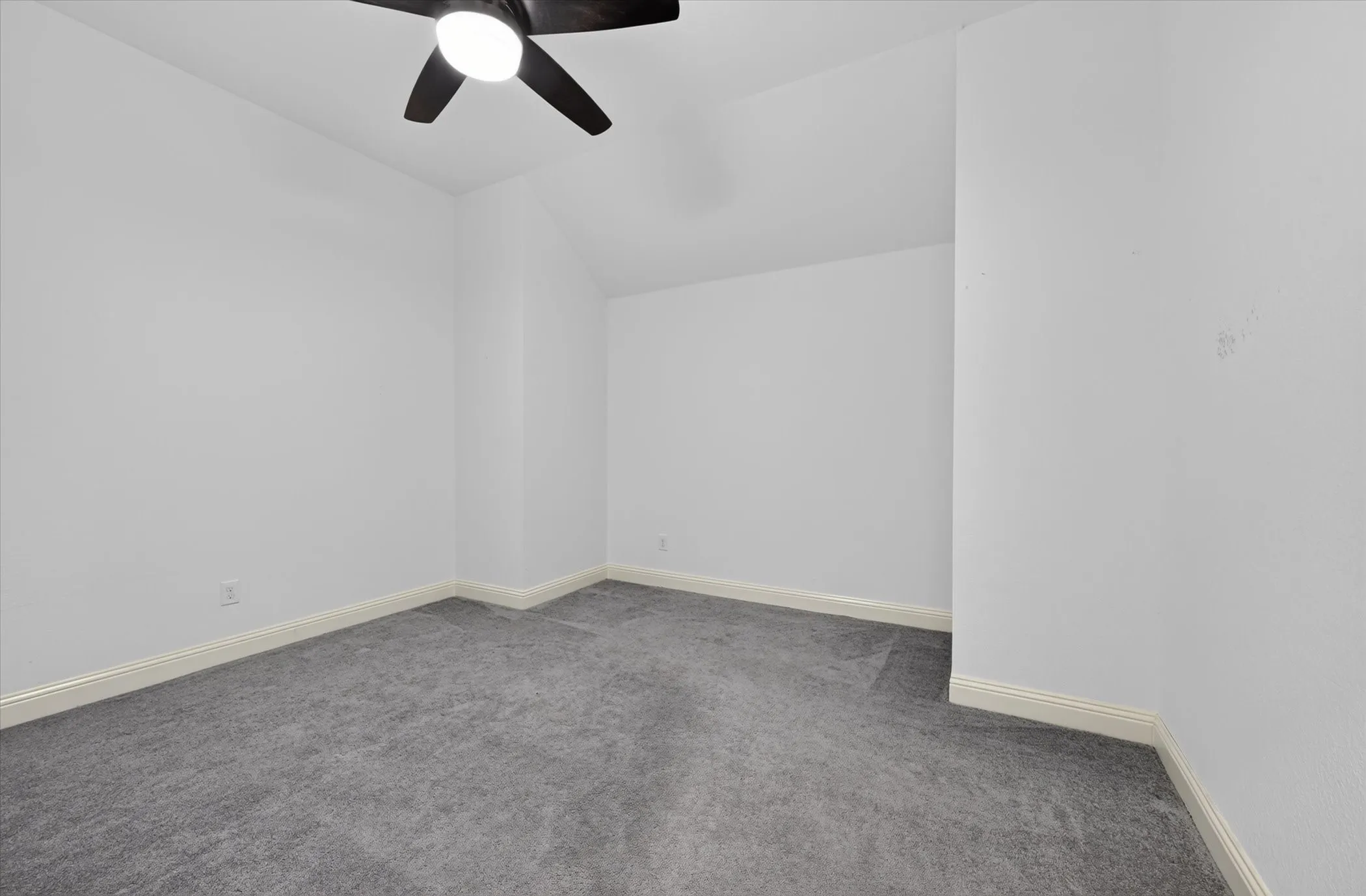 Vaulted ceiling with a ceiling fan, light gray carpeting, and white wall finishes