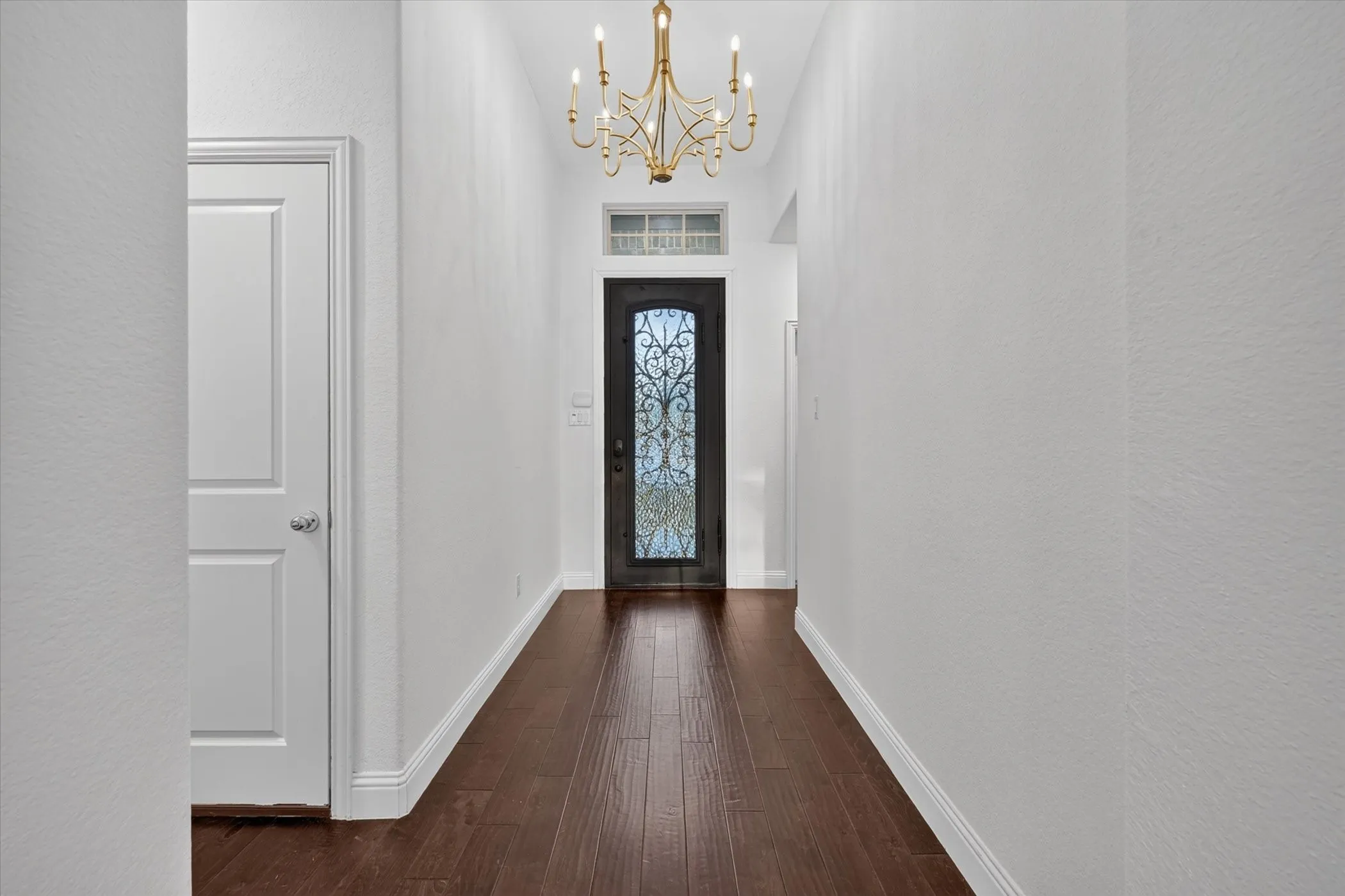 Wood-finish flooring leading to an ornate entry door with decorative glasswork