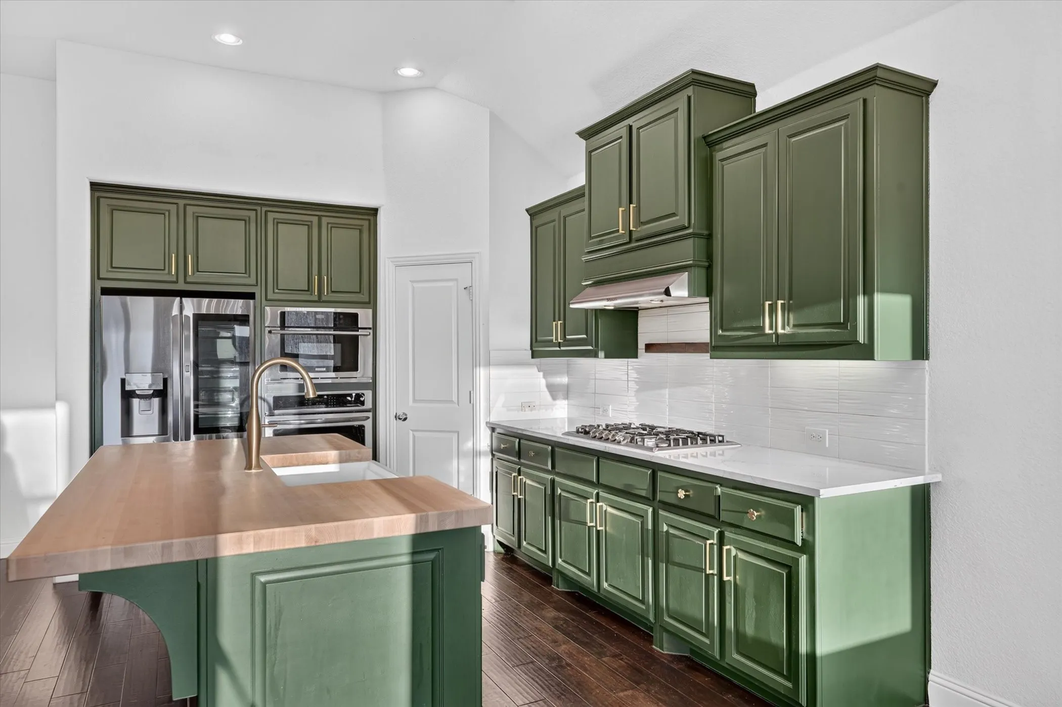 Kitchen featuring olive green cabinetry, stainless steel appliances, a gas cooktop, and a kitchen island with a built-in sink and wood-finish countertop