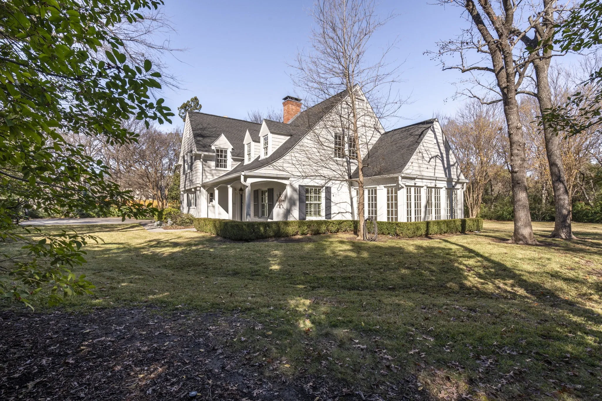 View of side of home featuring a lawn, a chimney, and covered porch