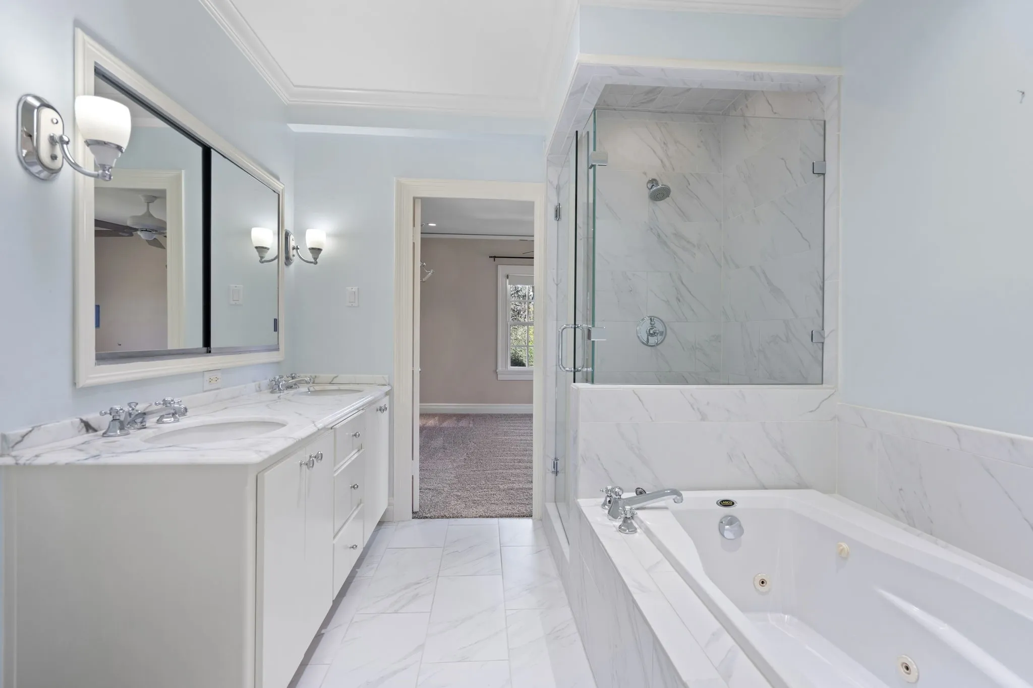 Full bath with double vanity, light marble finish flooring, a marble finish shower, a whirlpool tub, and ornamental molding