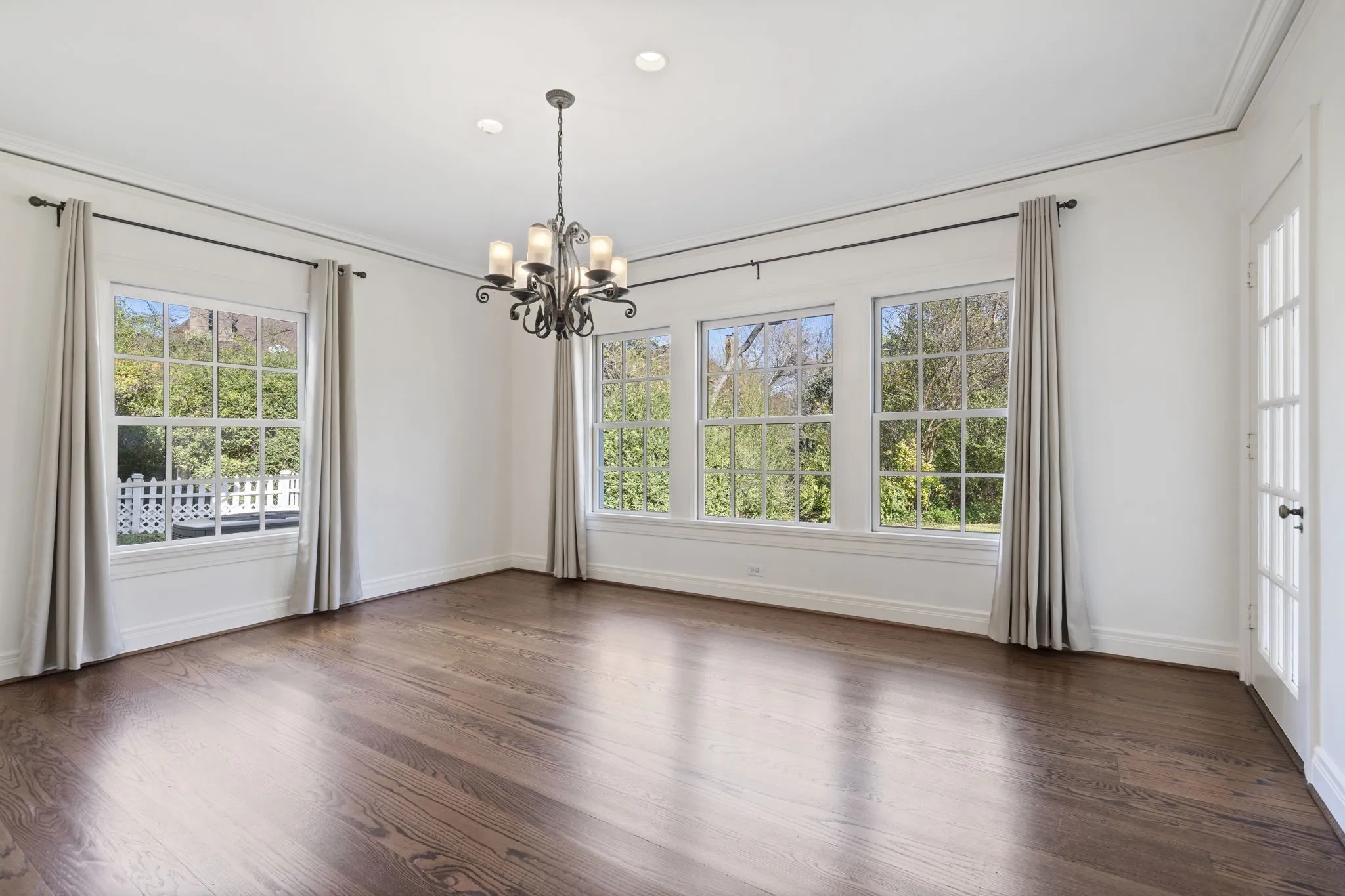 Empty room with dark wood-style floors, suspended lighting, and crown molding