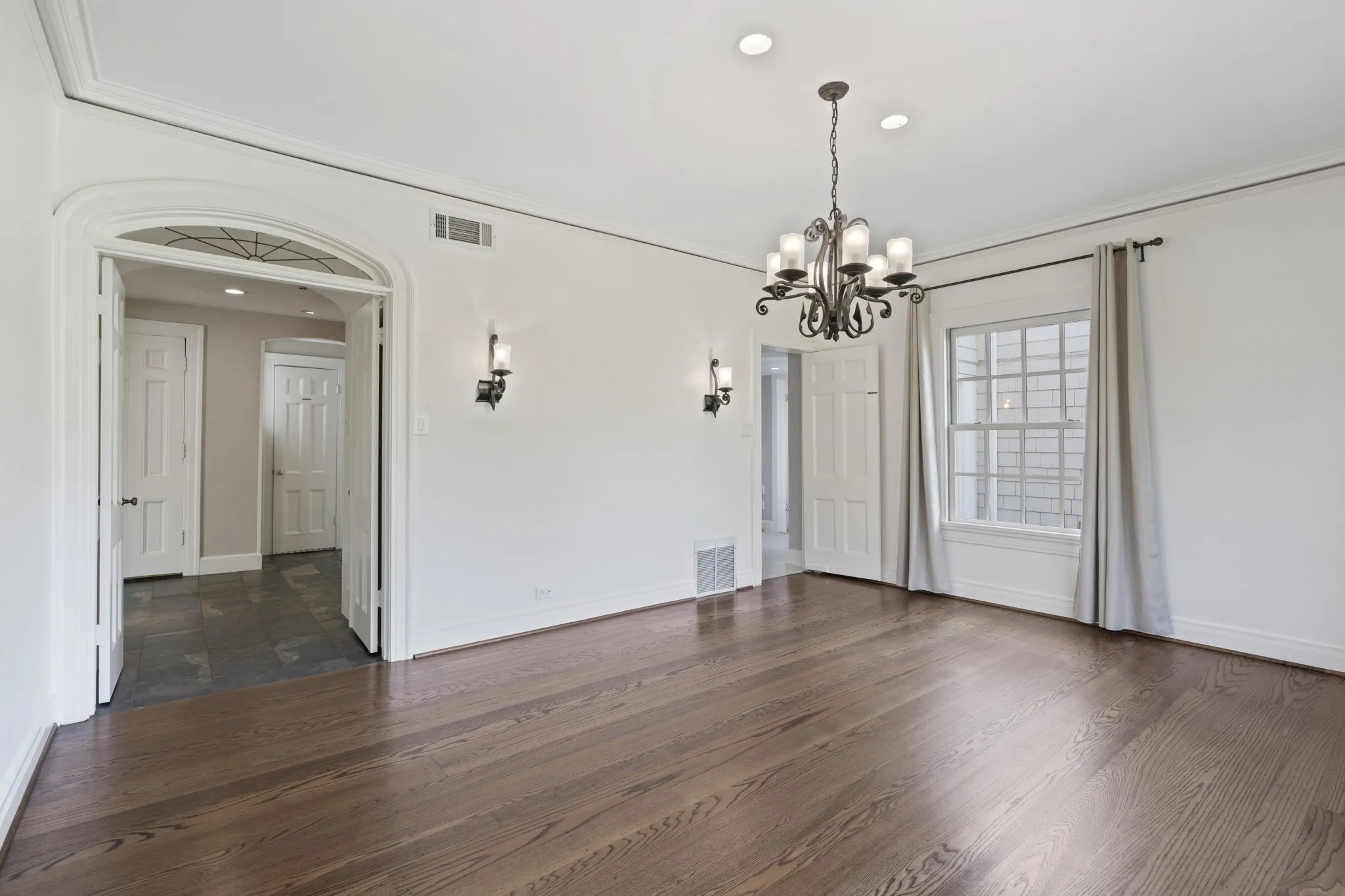Unfurnished dining area featuring a chandelier, crown molding, and dark wood-style floors