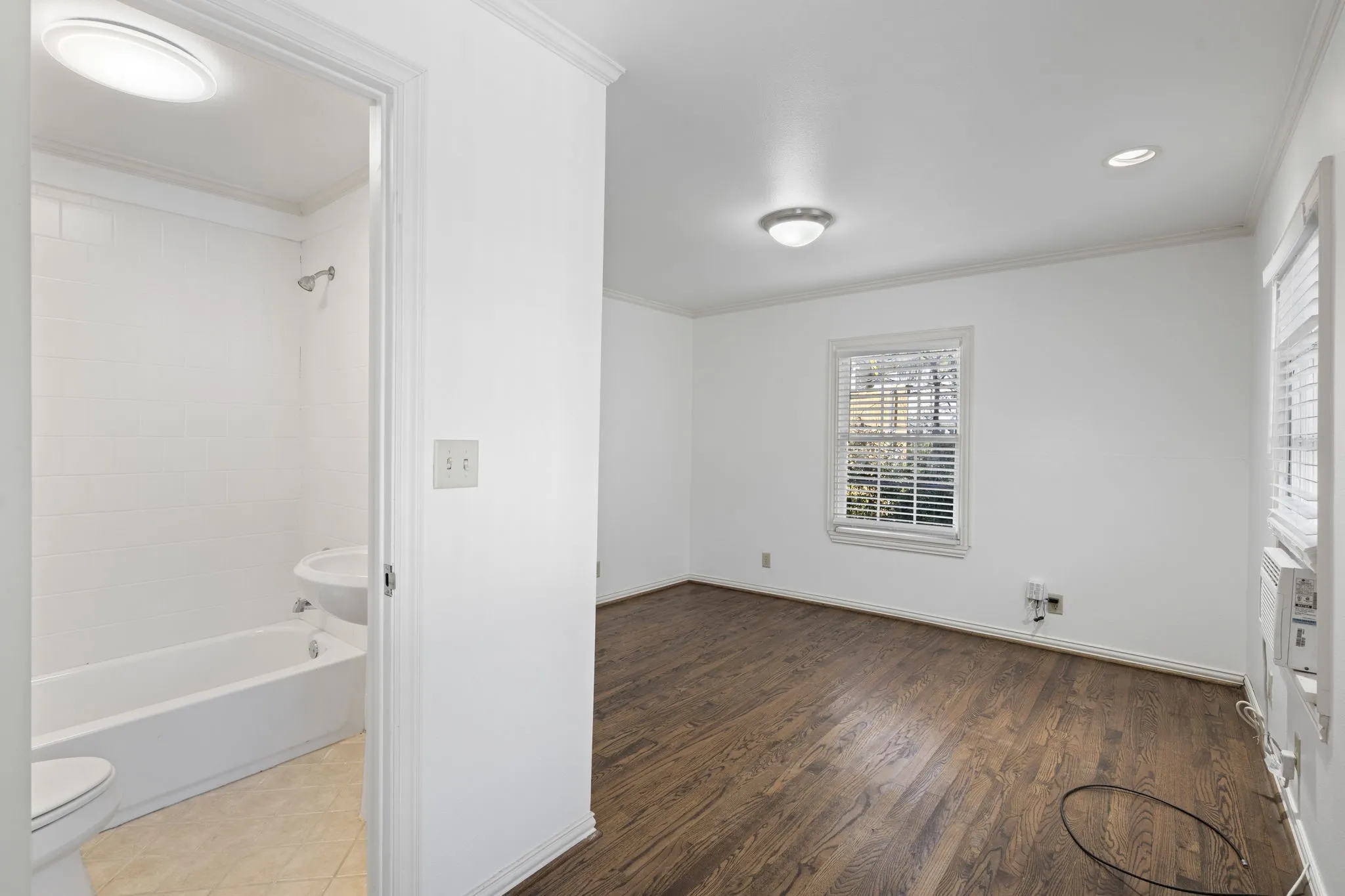 Unfurnished bedroom with crown molding, ensuite bathroom, dark wood-type flooring, and recessed lighting