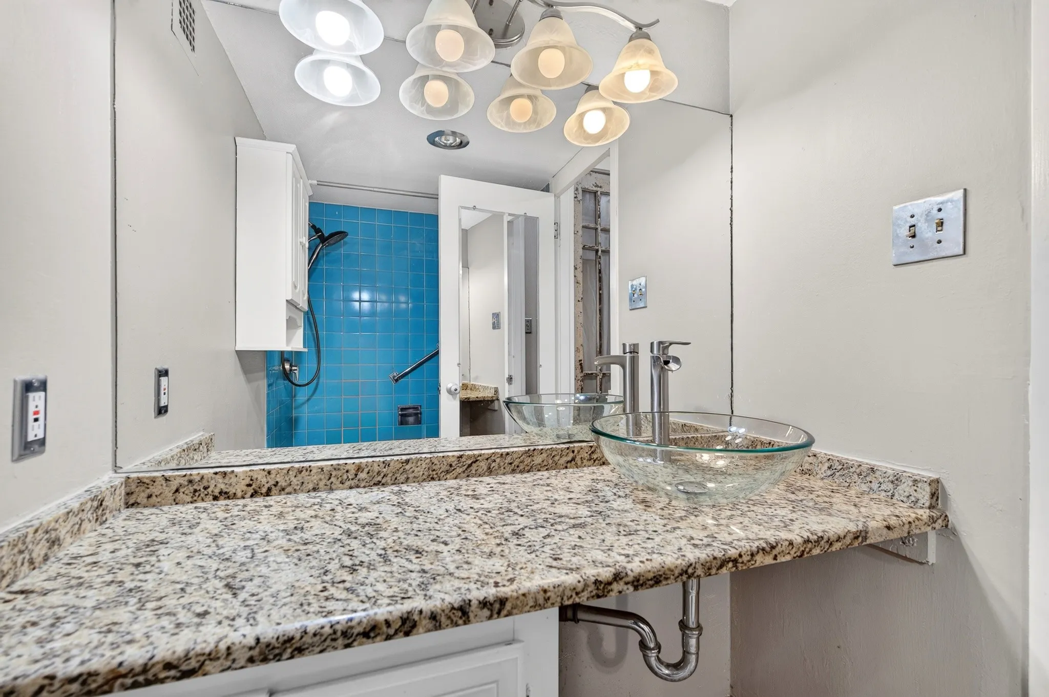 Granite-finish countertop with a glass vessel sink and chrome fixtures