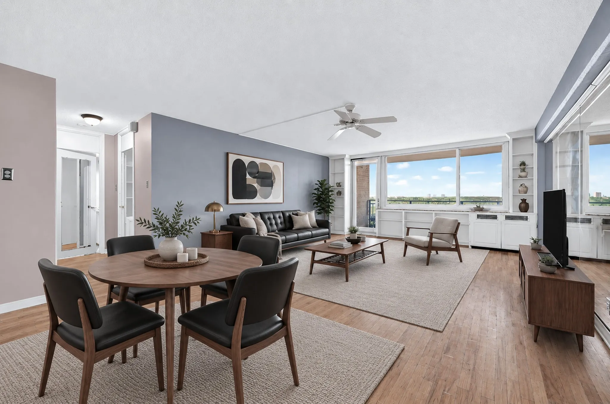 AI generated.
Expansive living space with wood flooring, a ceiling fan, and large windows