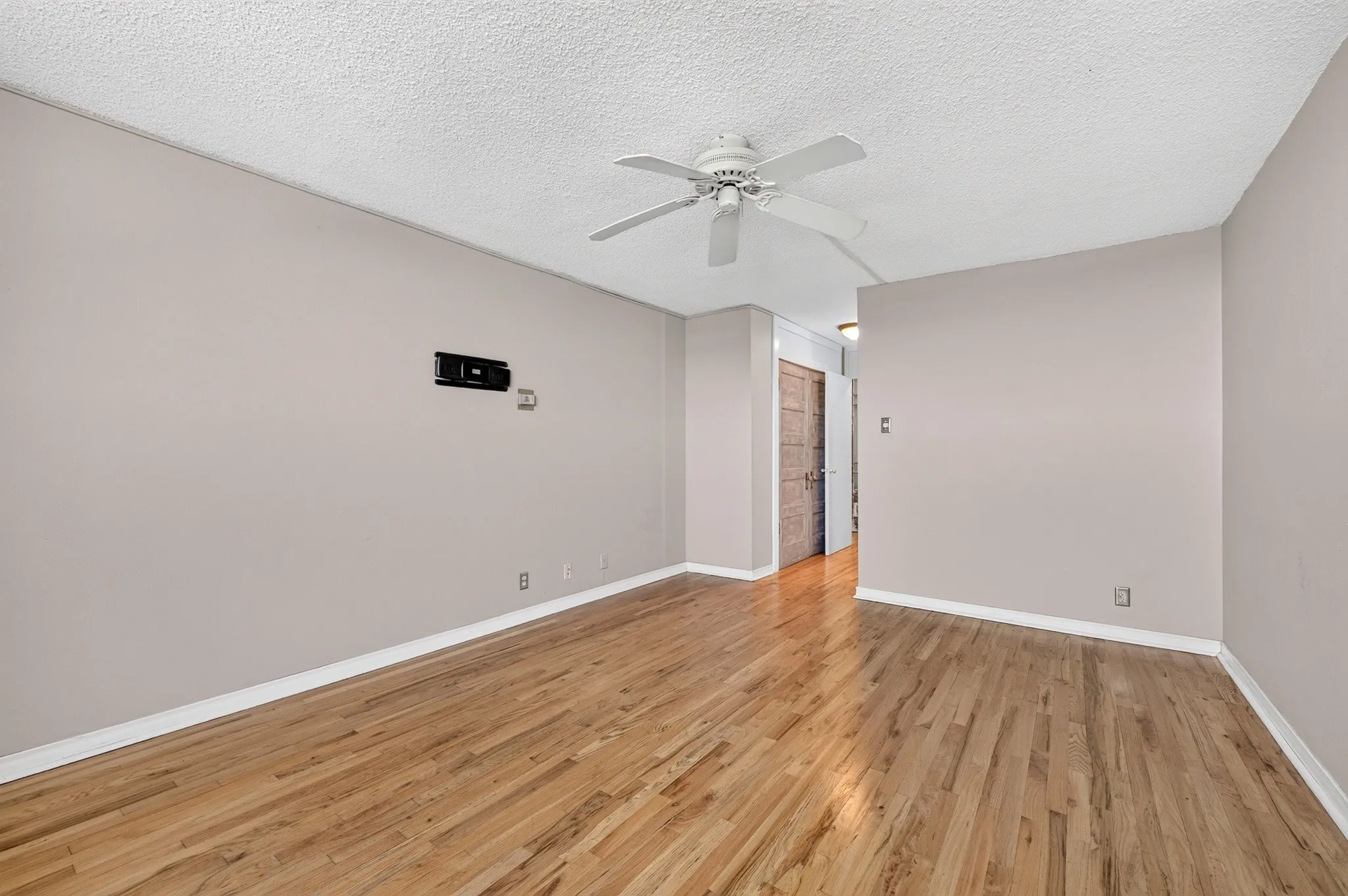 Hardwood flooring, neutral wall tones, white trim, ceiling fan, and textured ceiling
