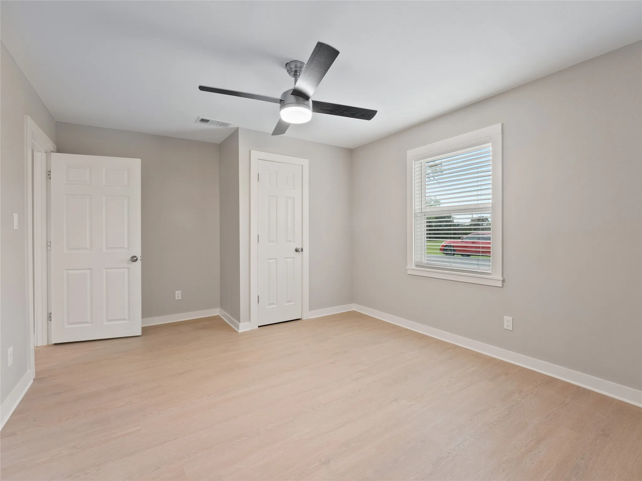 Bright room with wood-finish flooring, a modern ceiling fan, and white trim
