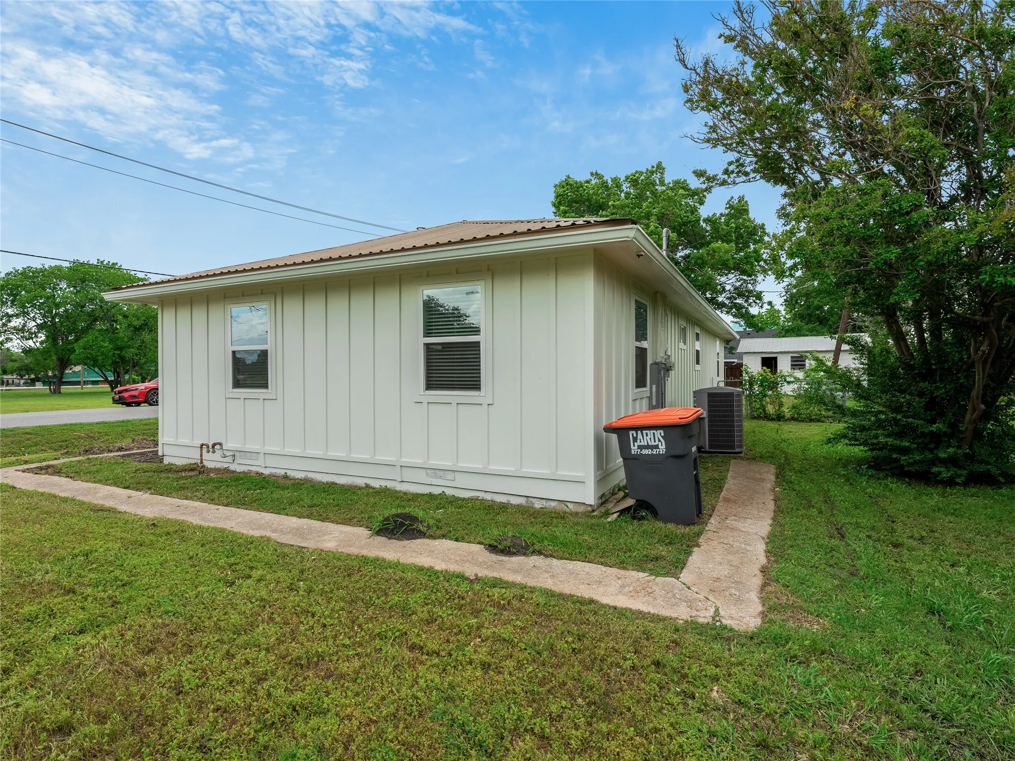 White siding exterior with a metal roof and multiple windows