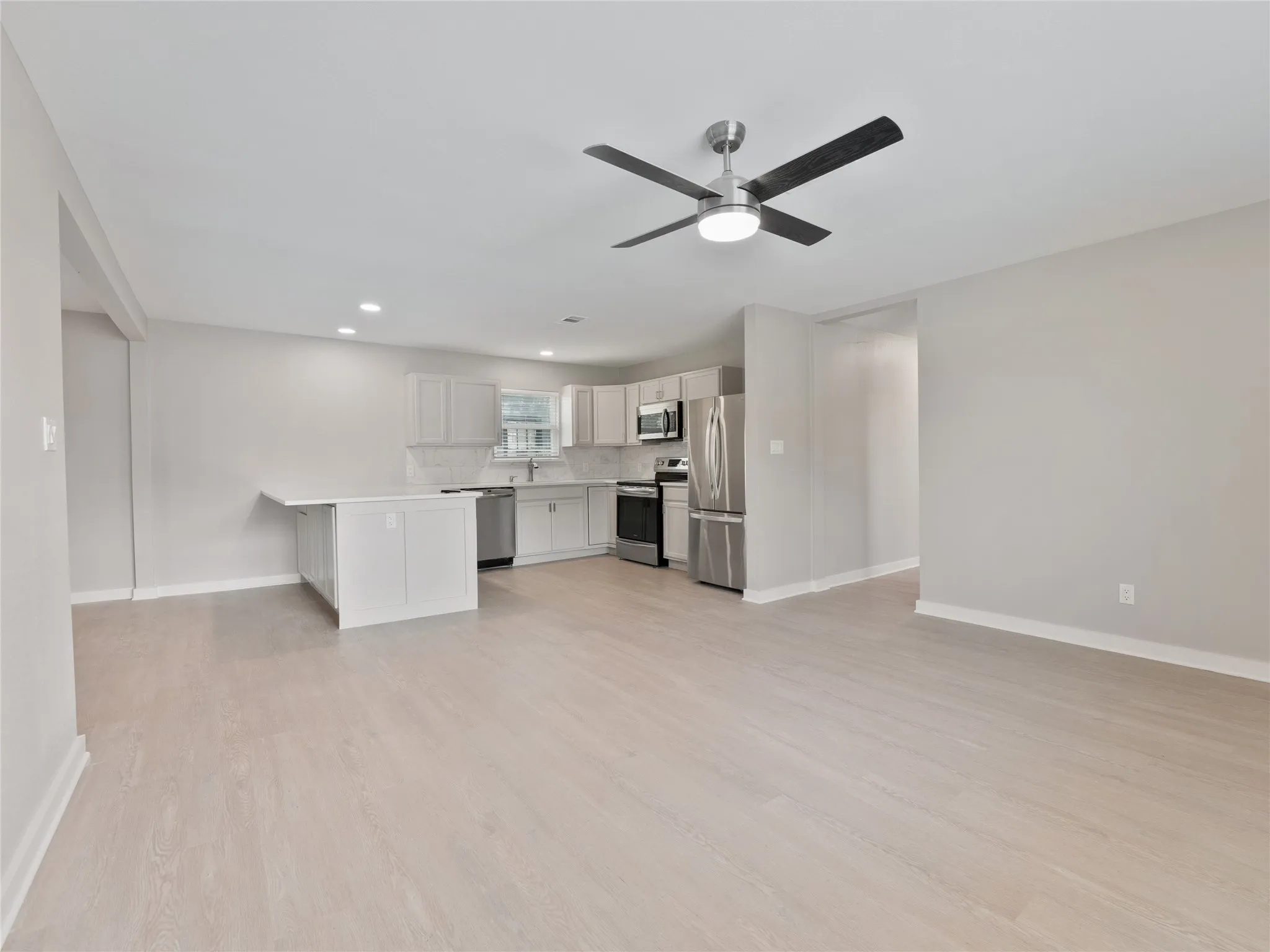 Kitchen area featuring white cabinetry, stainless steel appliances, and a central island with a breakfast bar