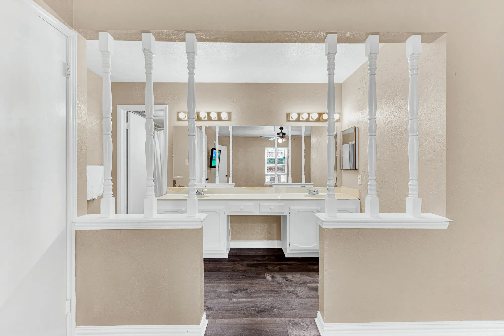 Dual vanity with white countertop and integrated sinks, individual mirrors, and wood-finish flooring