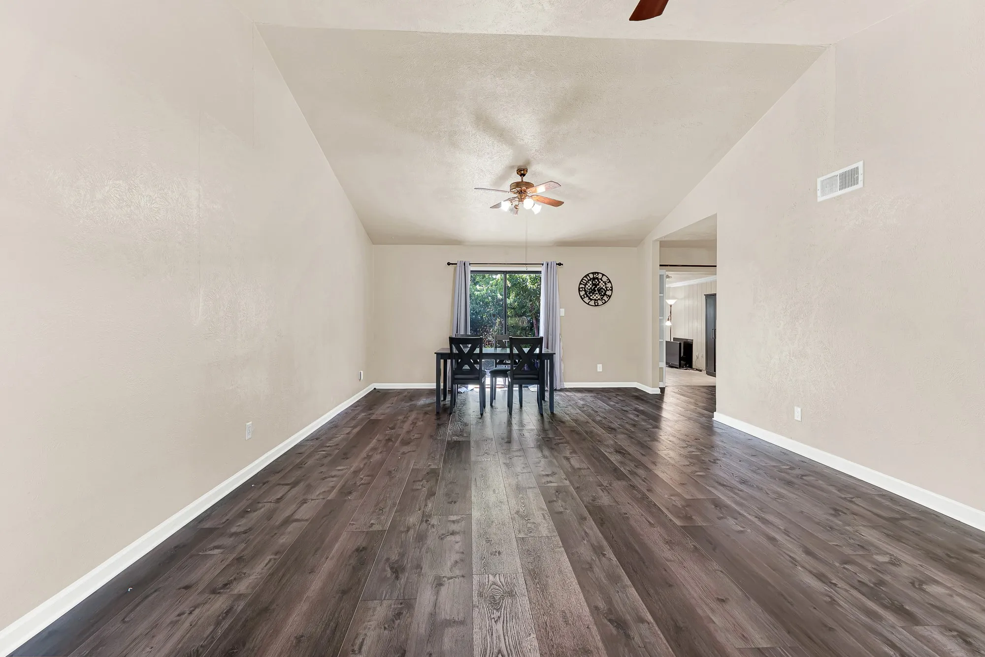 Vaulted ceiling with a ceiling fan, wood-finish flooring, and natural light from exterior window