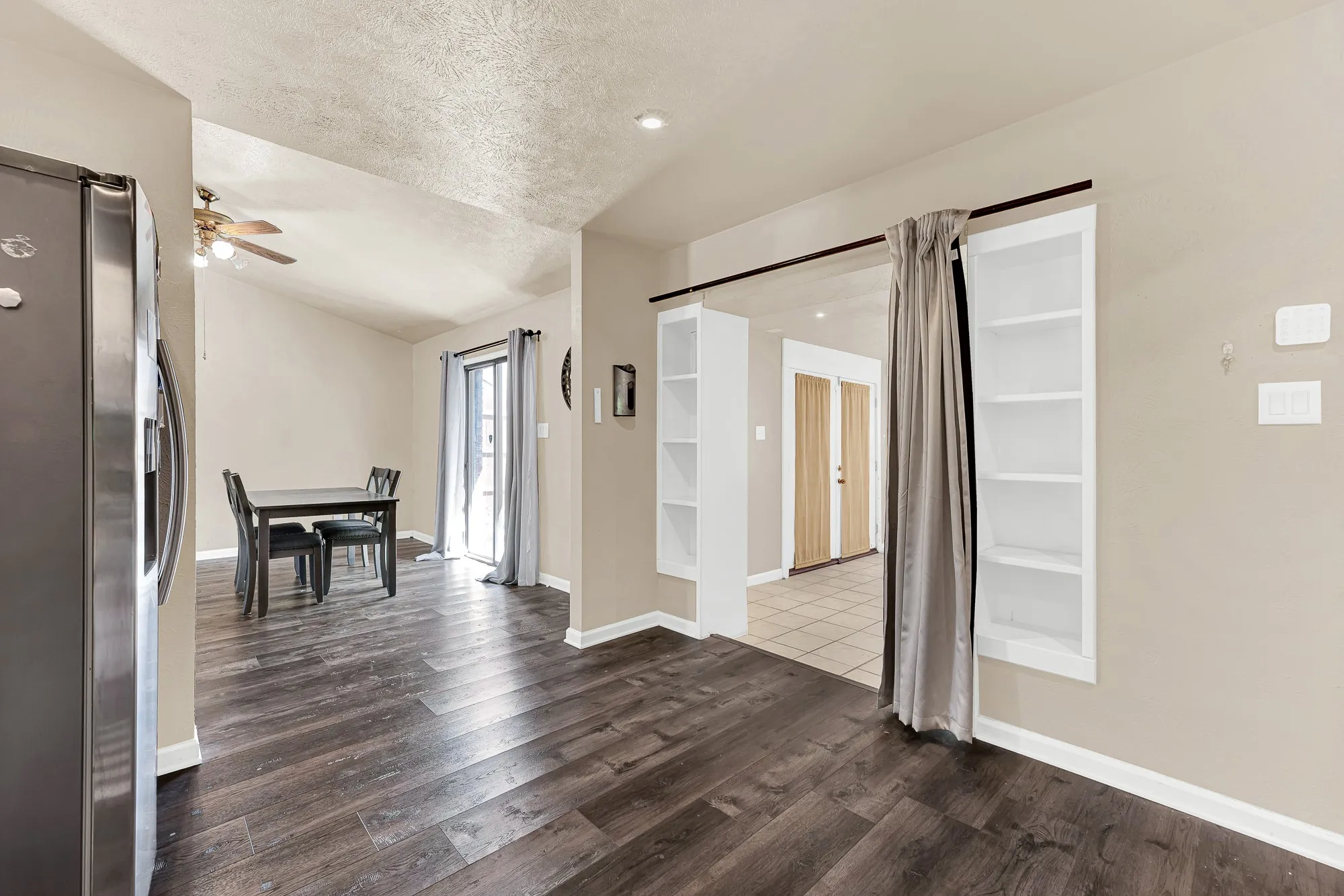 Wood-finish flooring throughout, vaulted ceiling, recessed lighting, built-in shelving, and a sliding glass door