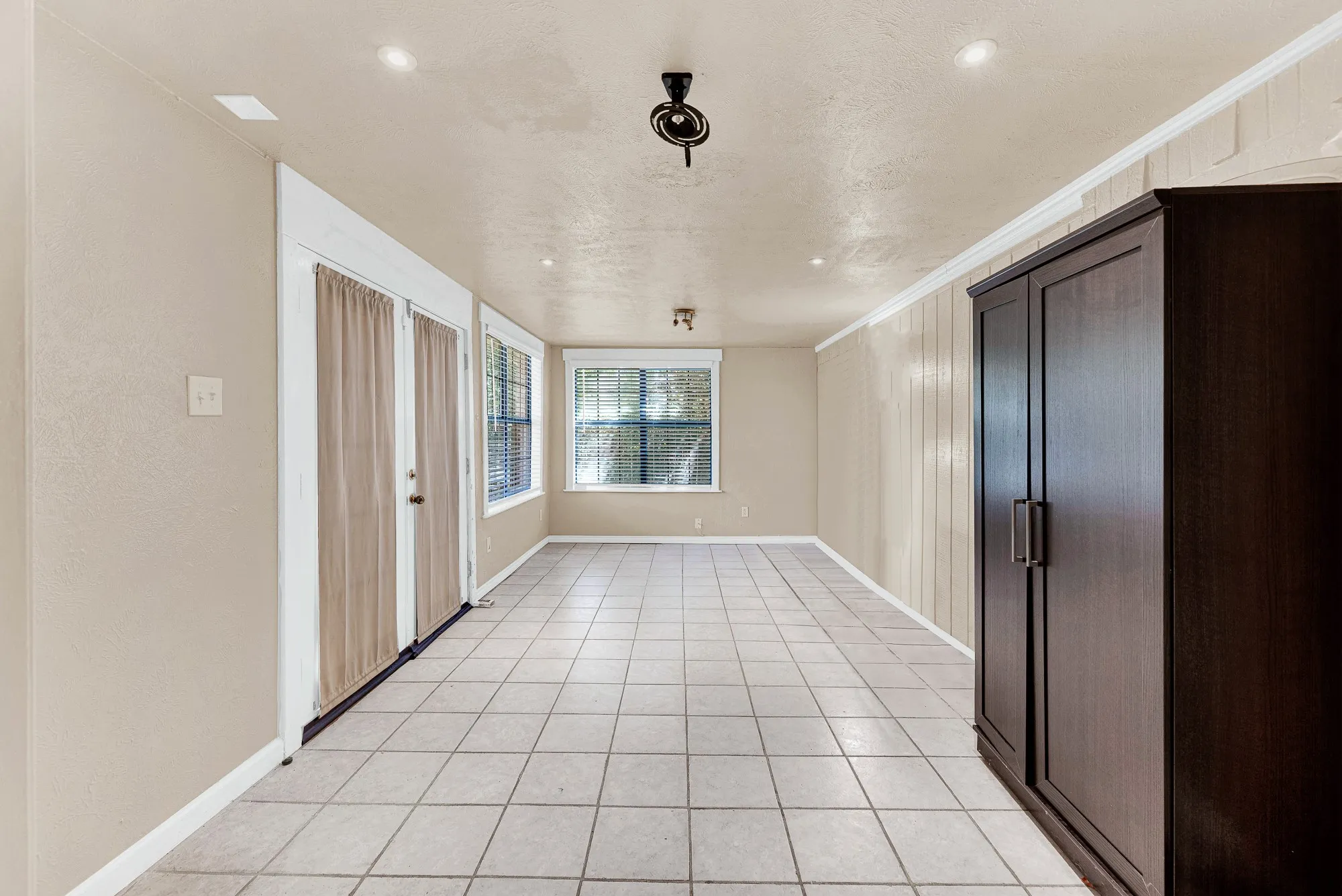 Tiled flooring, built-in shelving, painted brick accent wall, recessed lighting, and crown molding