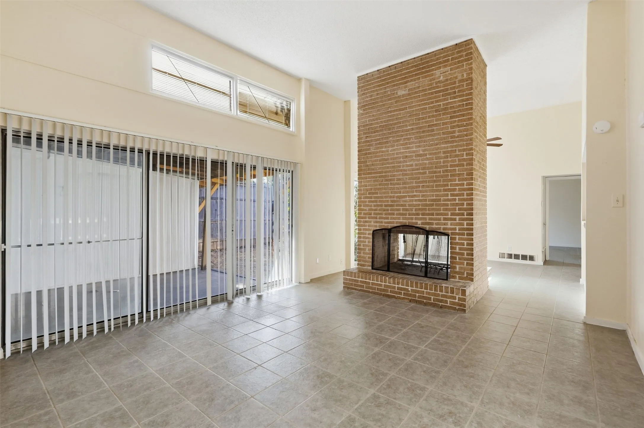 Tiled flooring, brick fireplace, and sliding glass doors