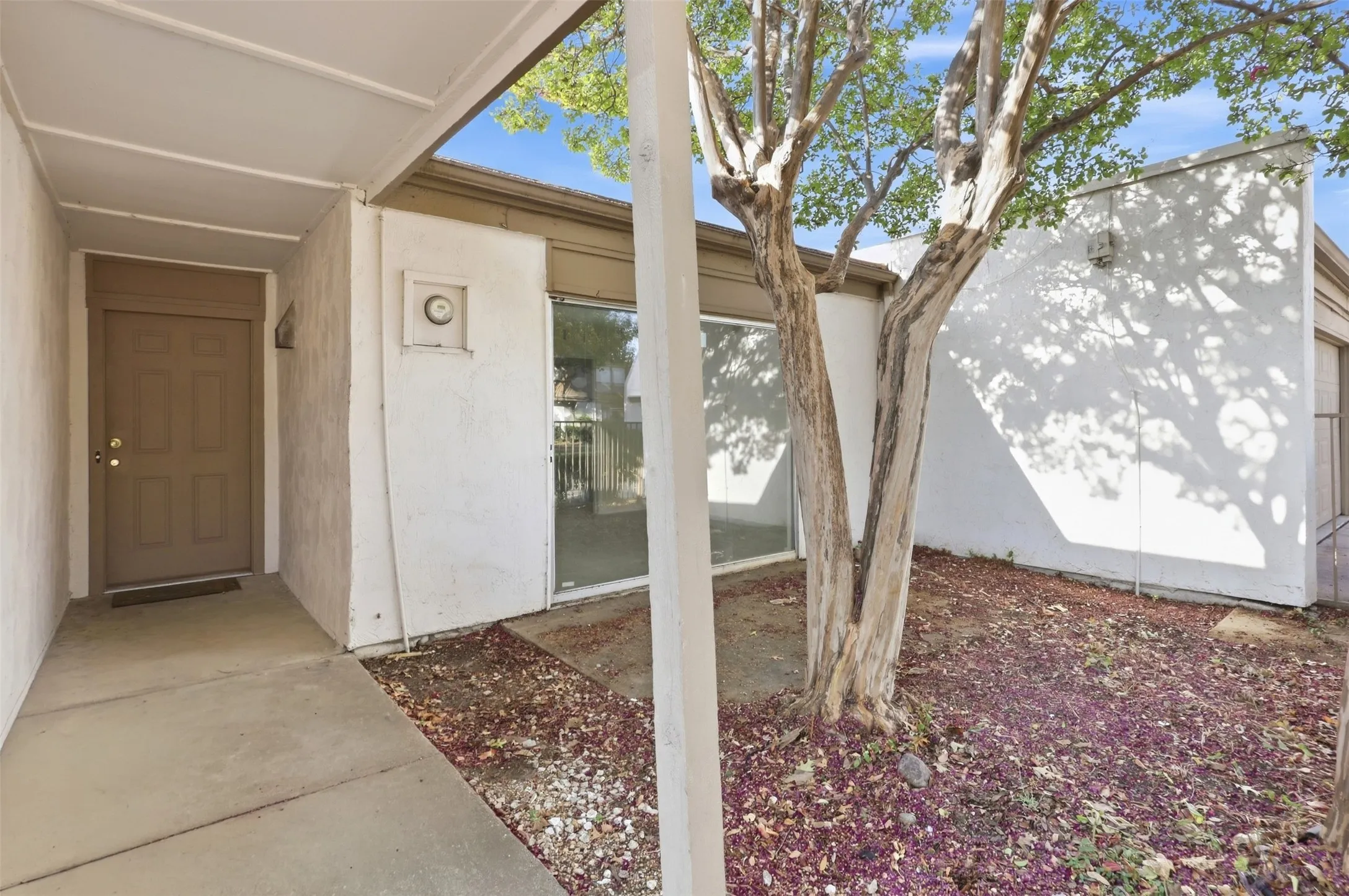 Covered entryway with concrete pathway, stucco exterior, and multi-pane windows
