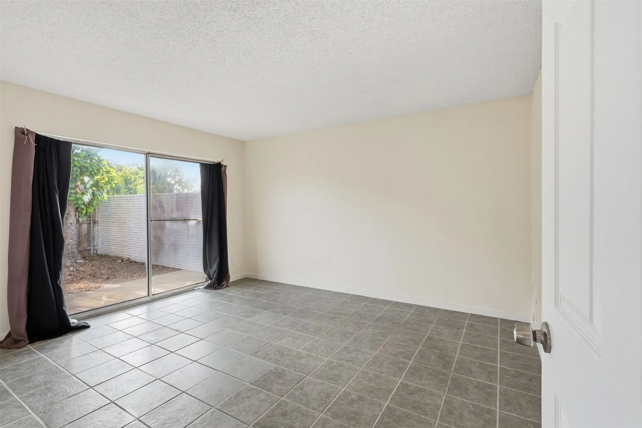 Sliding glass door, neutral-toned walls, tile flooring, textured ceiling, paneled interior door