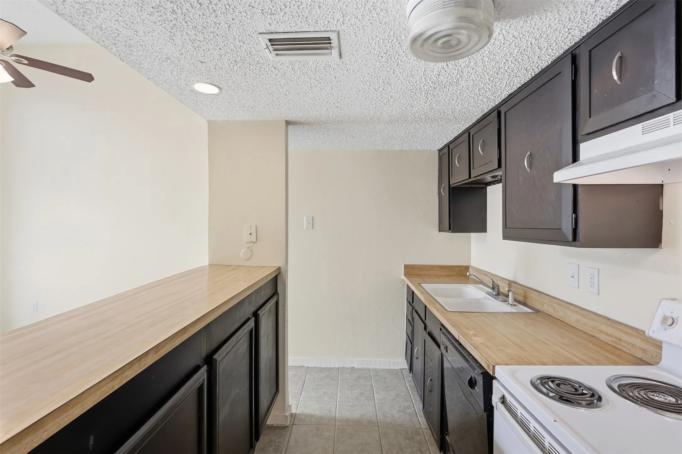 Kitchen featuring dark cabinetry, wood-finish countertops, and tile flooring