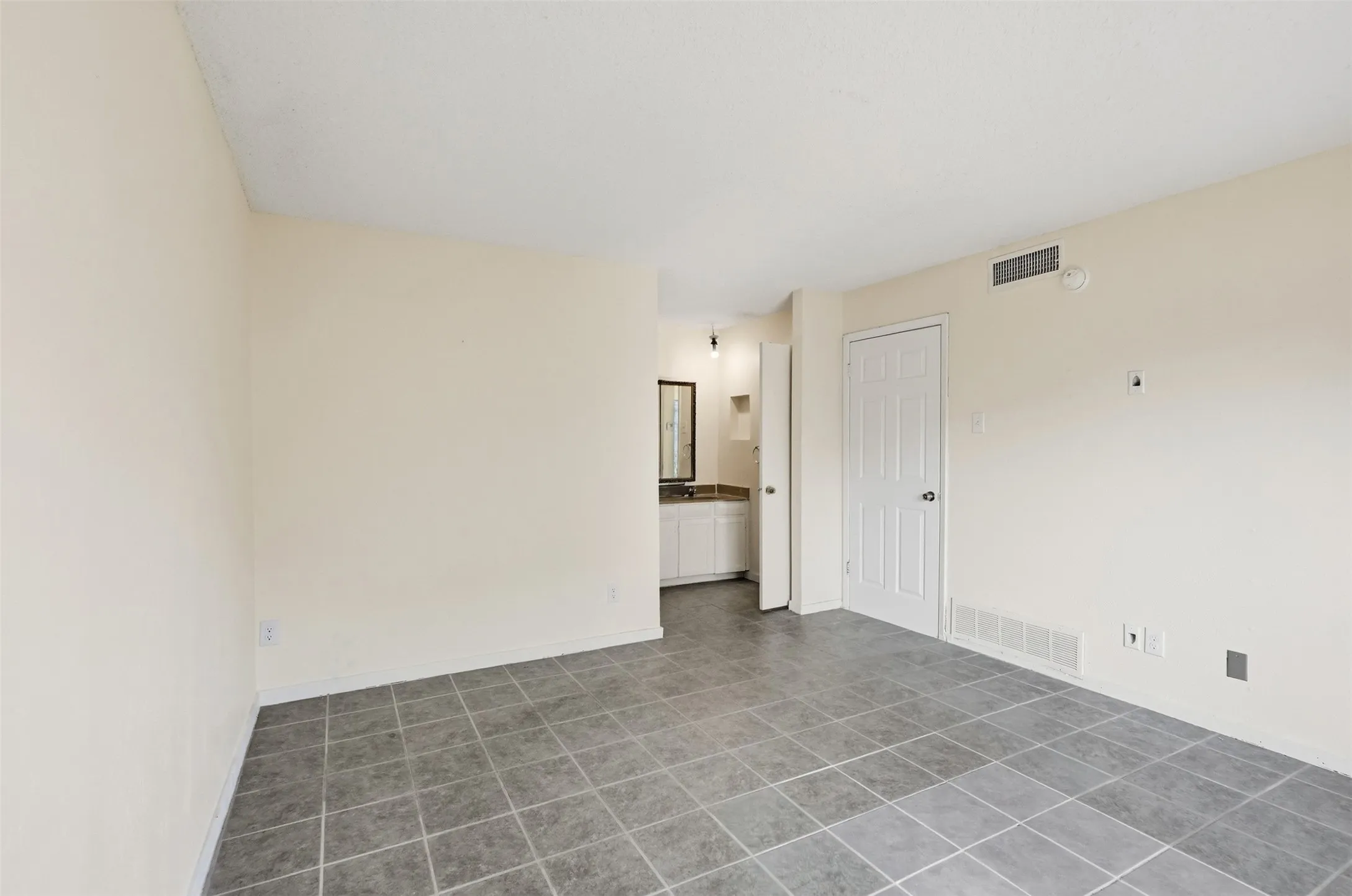 Gray tile flooring, neutral wall finishes, and a white interior door