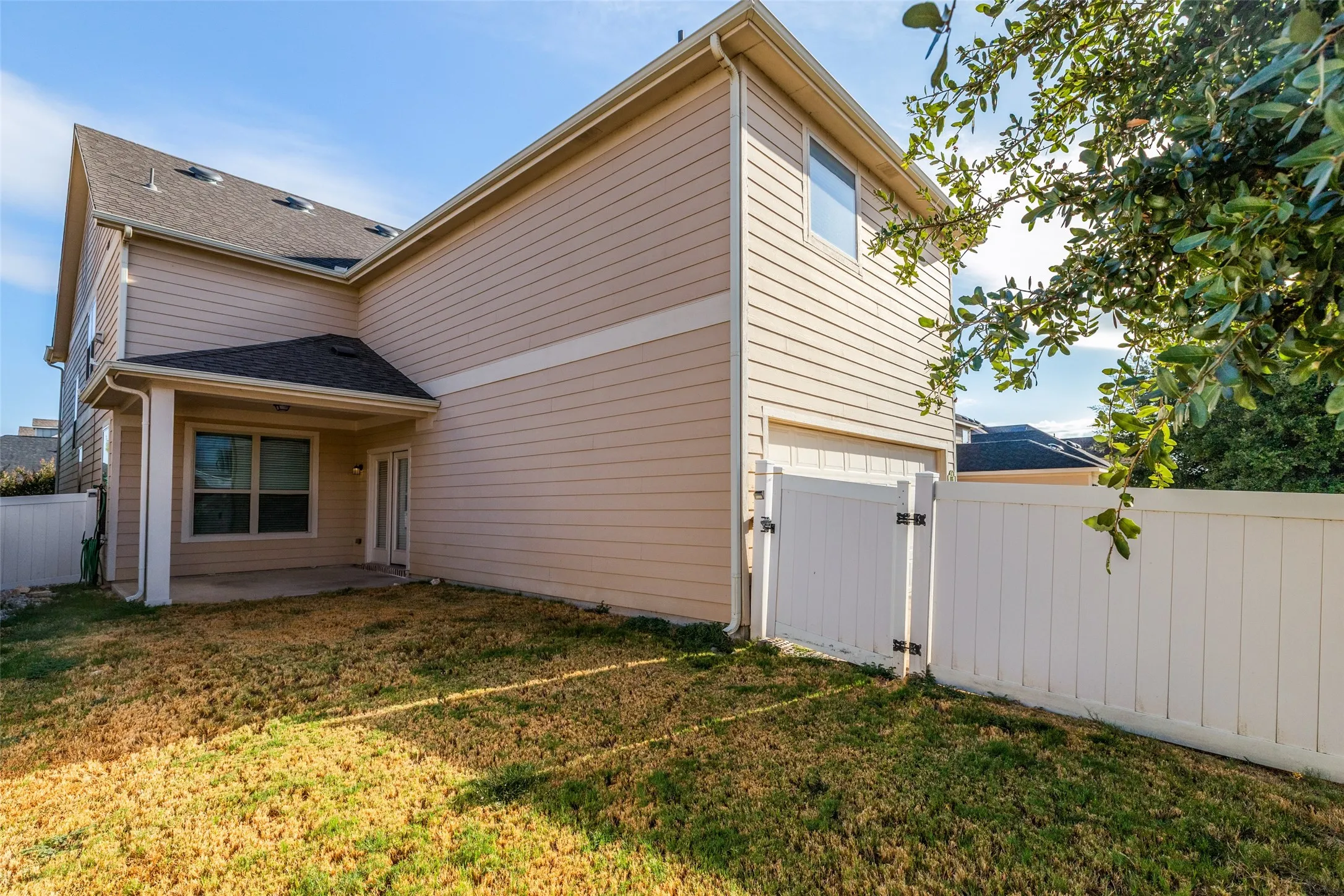 Exterior featuring vinyl siding, an attached covered patio, a privacy fence, and a gate