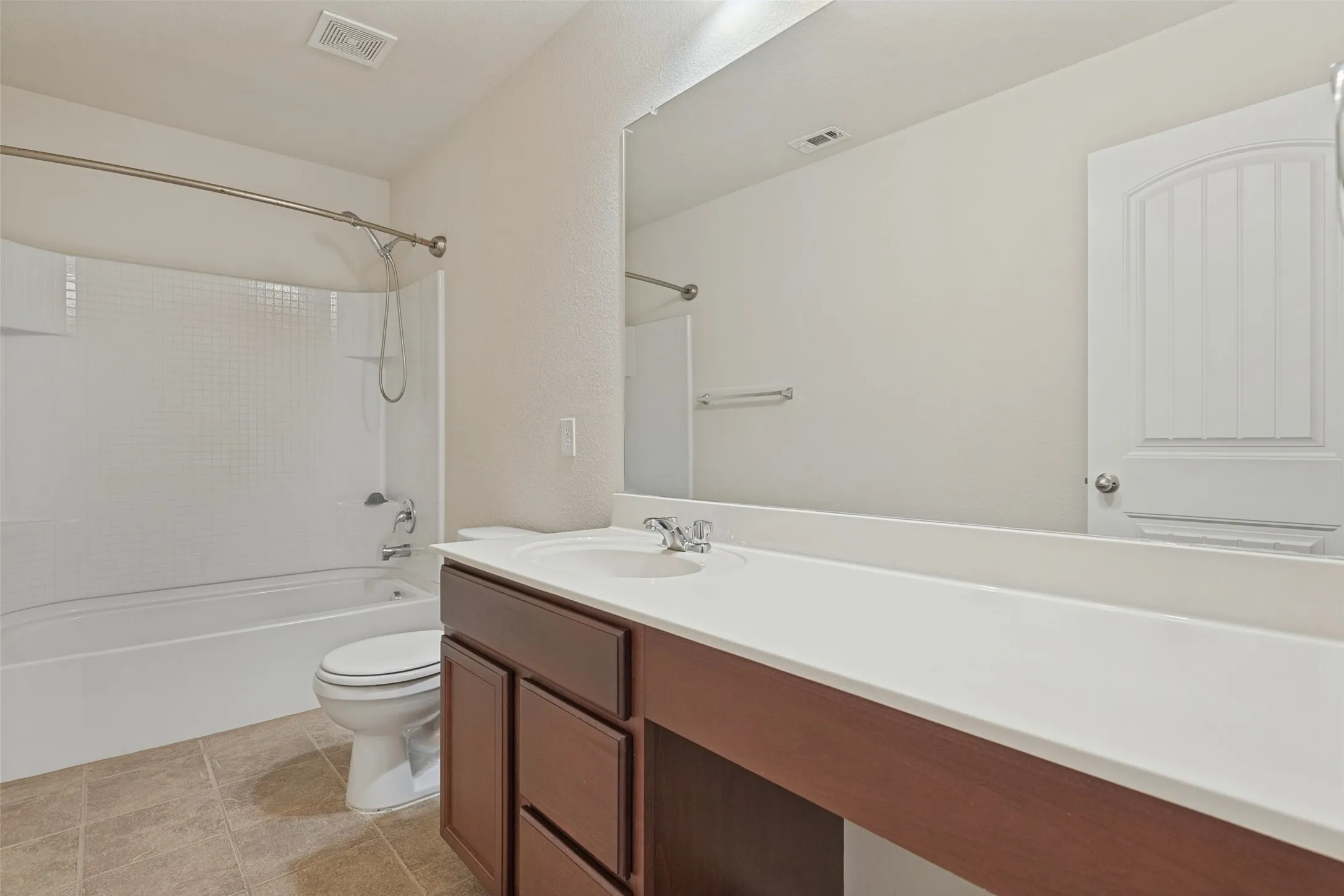 Bathroom featuring a single vanity with dark wood-finish cabinetry, a white countertop, and a large wall-mounted mirror