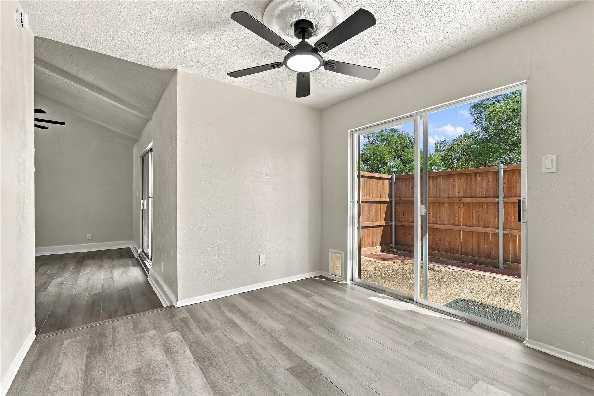 Wood-finish flooring throughout, with a matte black ceiling fan