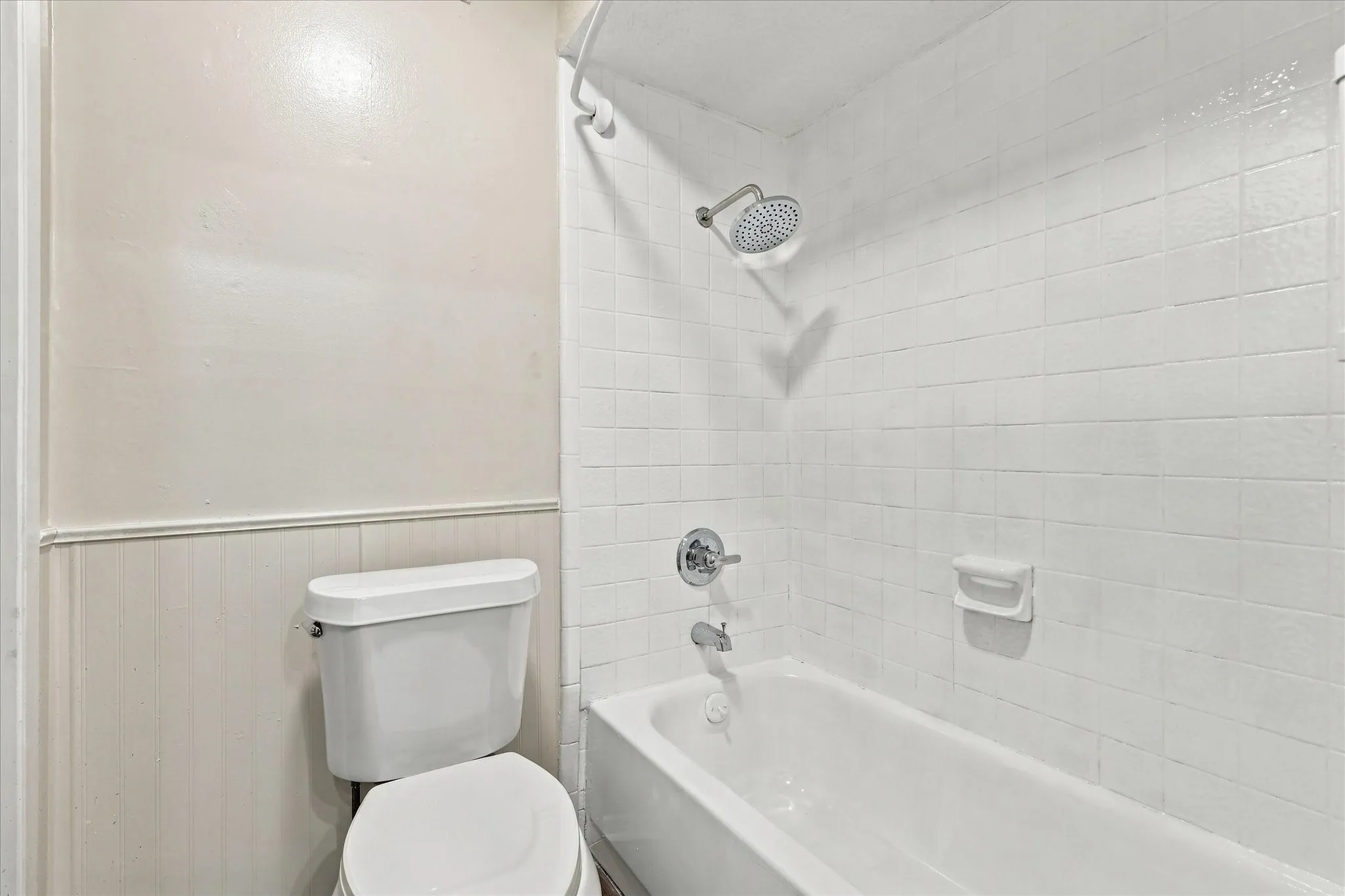 Bathtub with subway tile surround, chrome showerhead, and matching fixtures