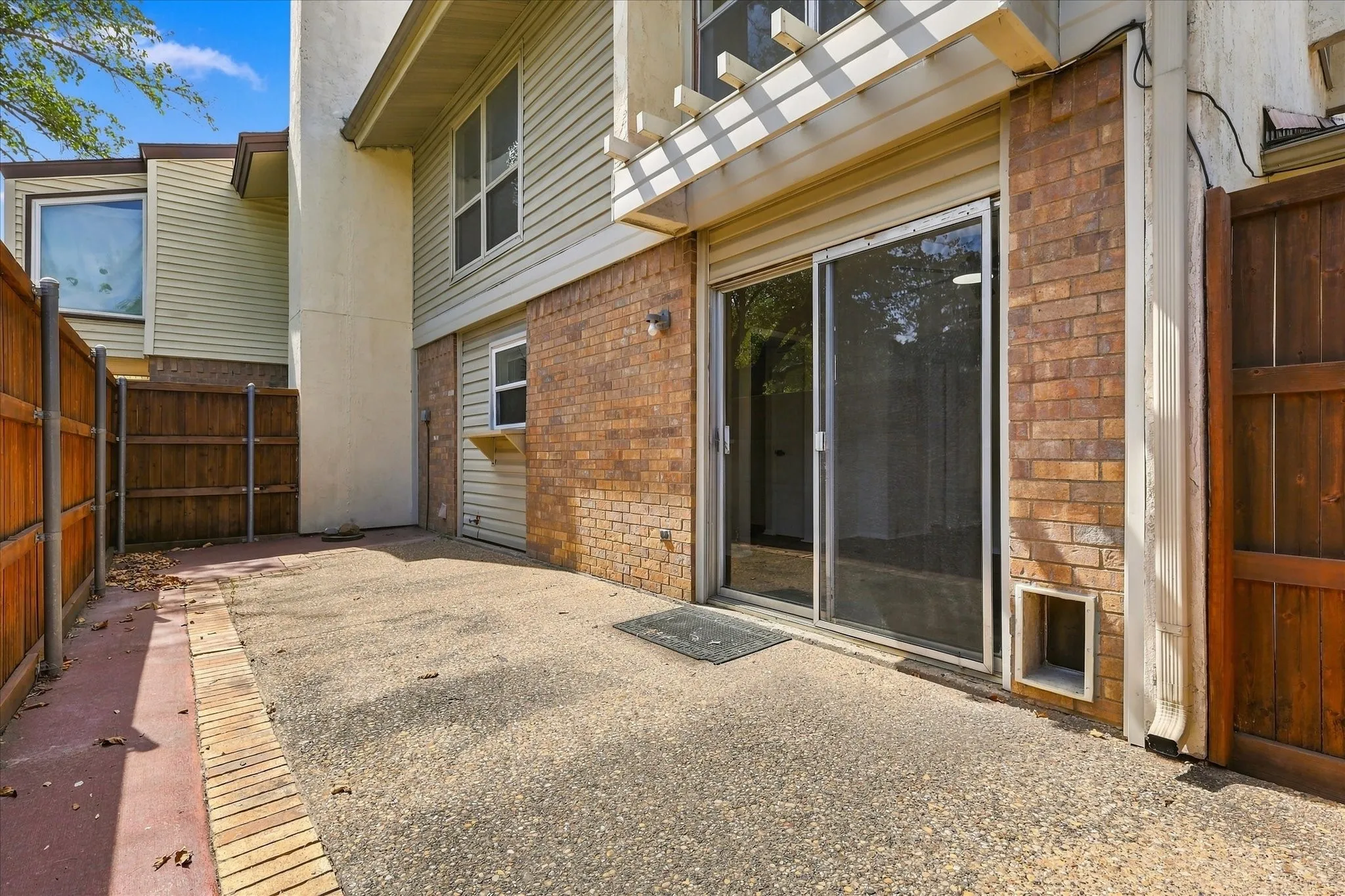 Private patio with textured concrete surface, brick and siding exterior, sliding glass door, and privacy fencing
