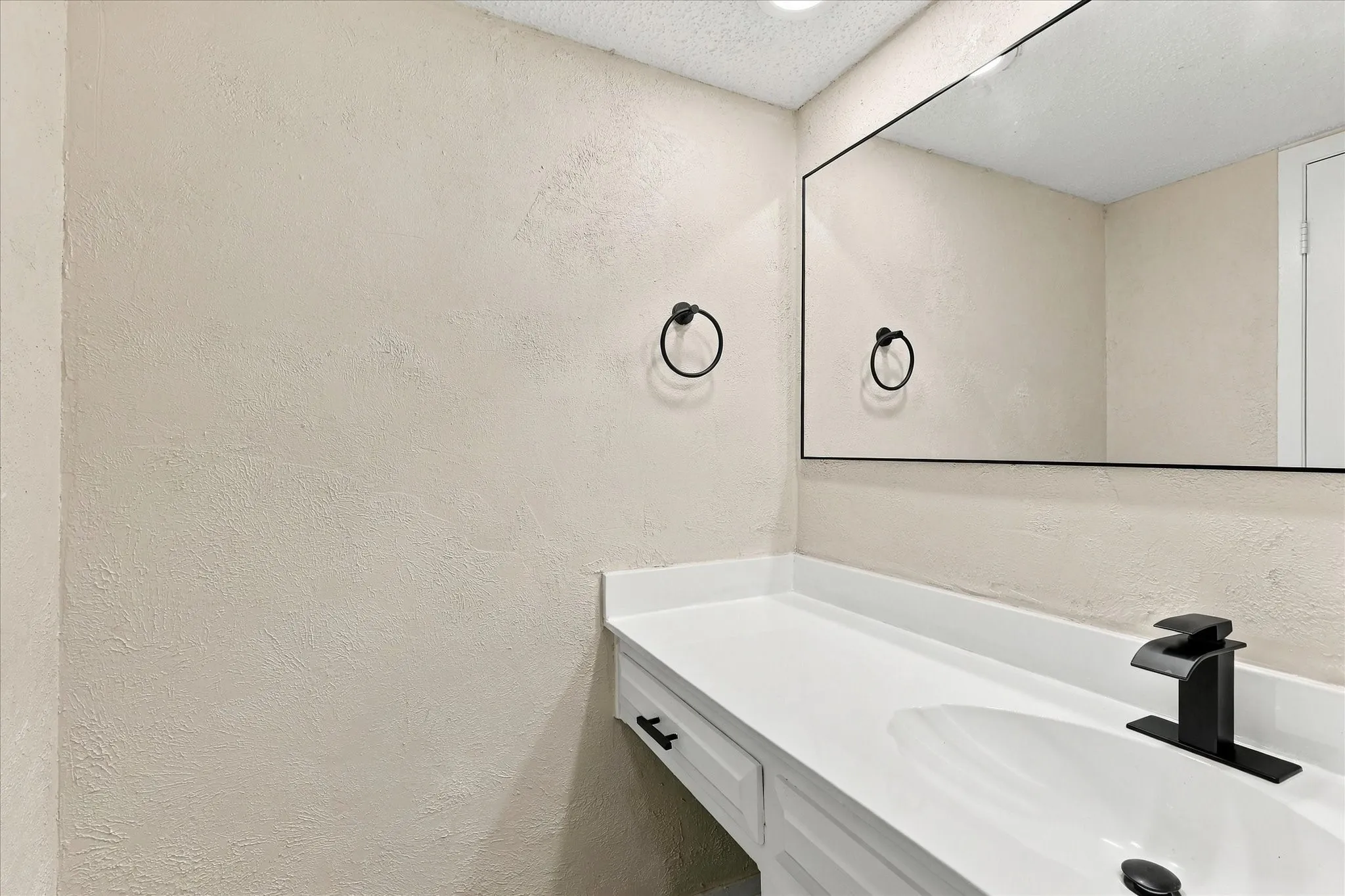Vanity with white countertop, integrated sink, and matte black faucet