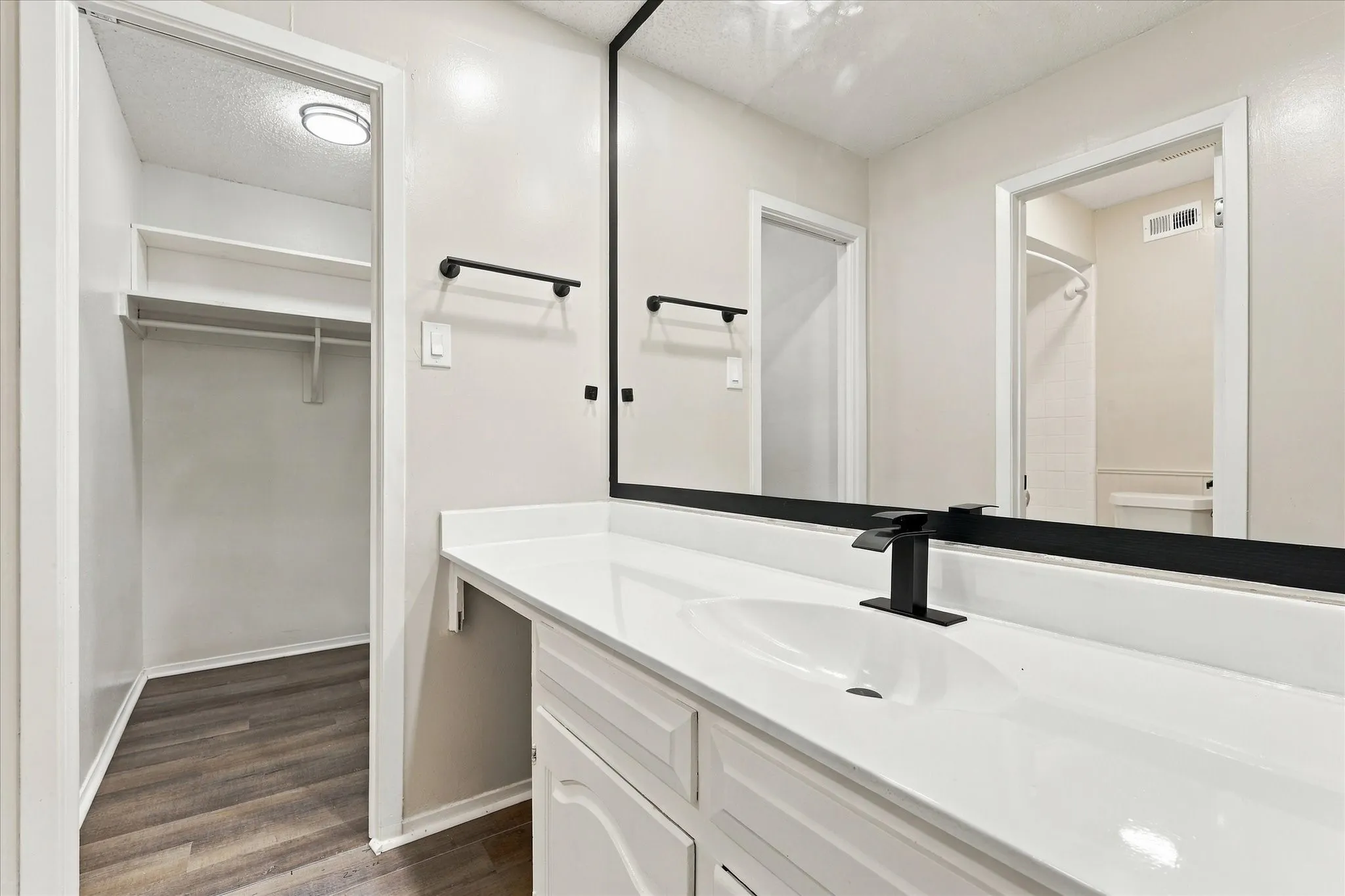 White vanity with integrated sink, black single-handle faucet, and oversized mirror