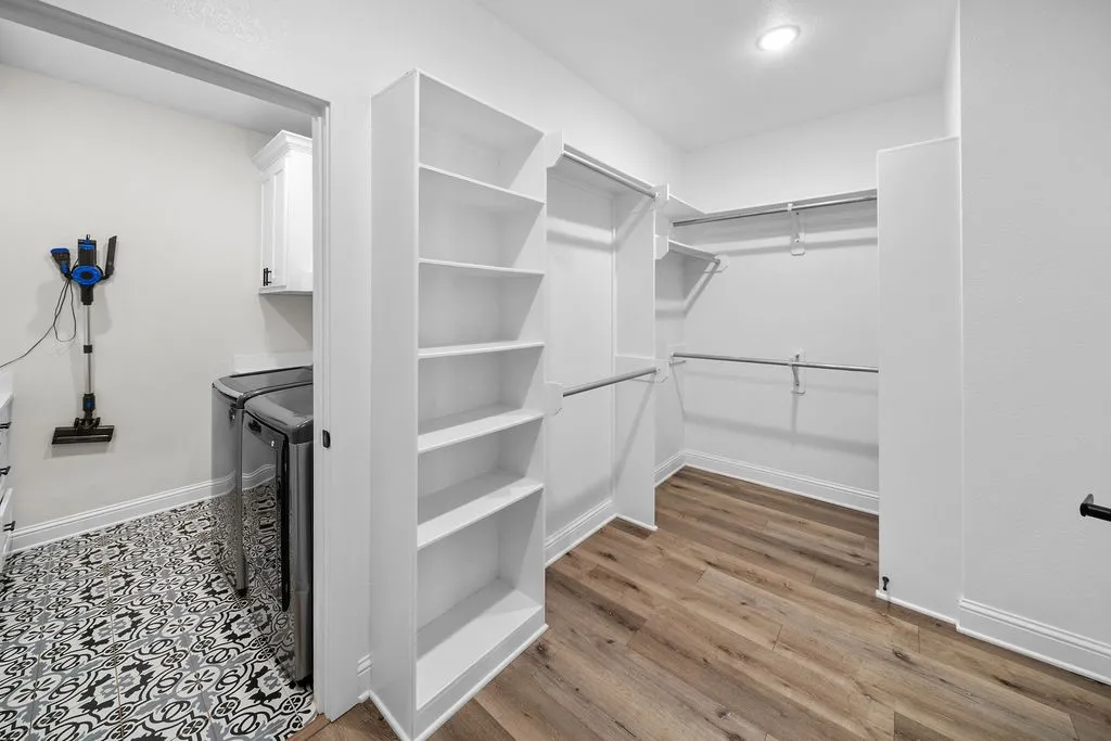 Walk-in closet with wood-finish flooring, built-in shelving, and metal hanging rods