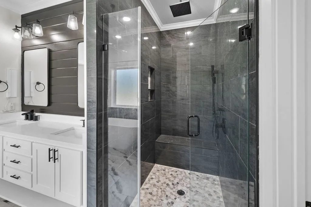 Glass-enclosed shower with stone tile surround, integrated bench, and rainfall showerhead