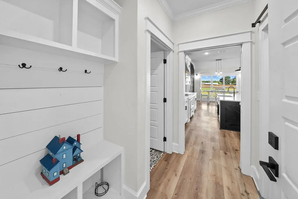 Built-in mudroom seating with storage, wood-finish flooring, and white paneled doors with matte black hardware