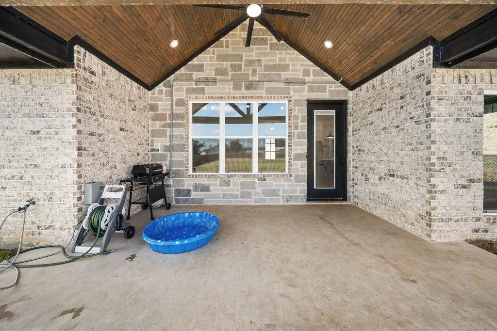 Expansive covered patio featuring a wood-finish ceiling, exposed beam accents, and integrated ceiling fan