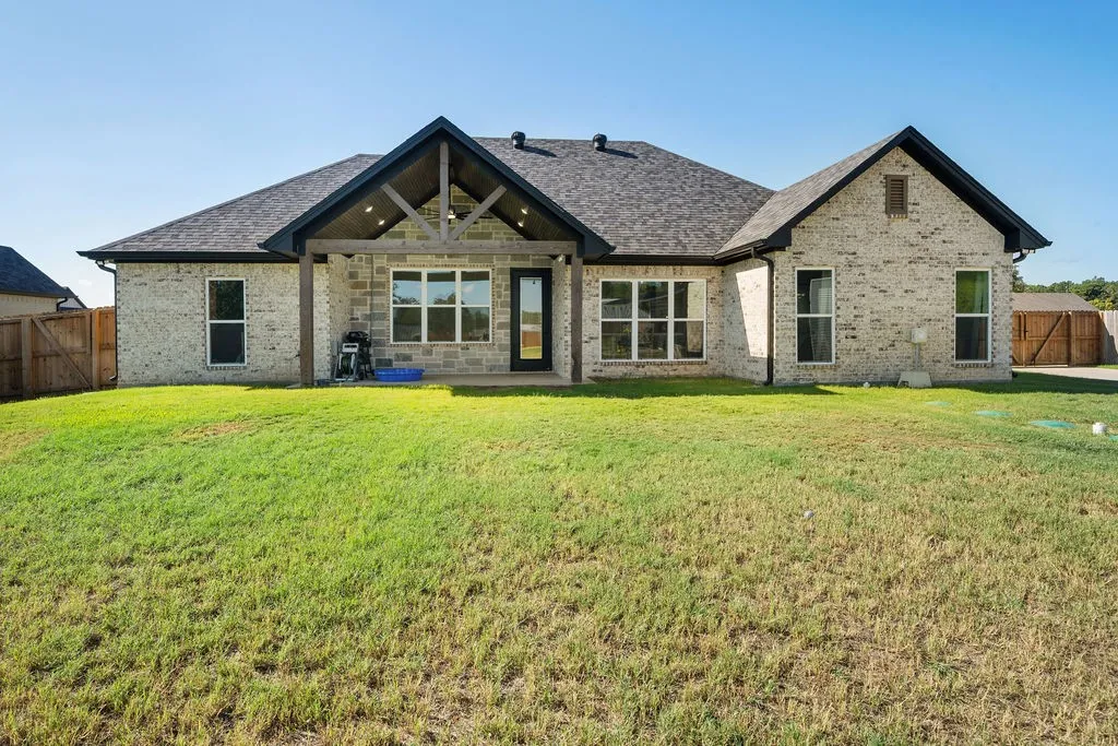 Light-toned brick exterior with a dark shingle roof and black trim