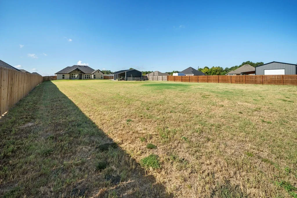 Spacious yard featuring a full wood fence and ample green space