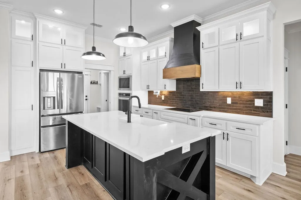 Gourmet kitchen featuring white shaker cabinetry, stainless steel appliances, a black wood-finish island, quartz countertops, and wood-finish flooring