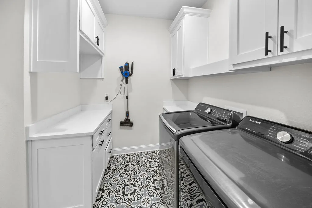 White shaker-style cabinetry with black hardware, white countertops, and patterned tile flooring