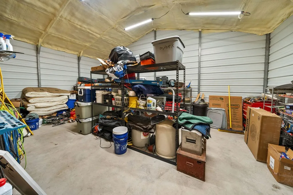 Corrugated metal walls with a high ceiling, concrete flooring, and fluorescent lighting